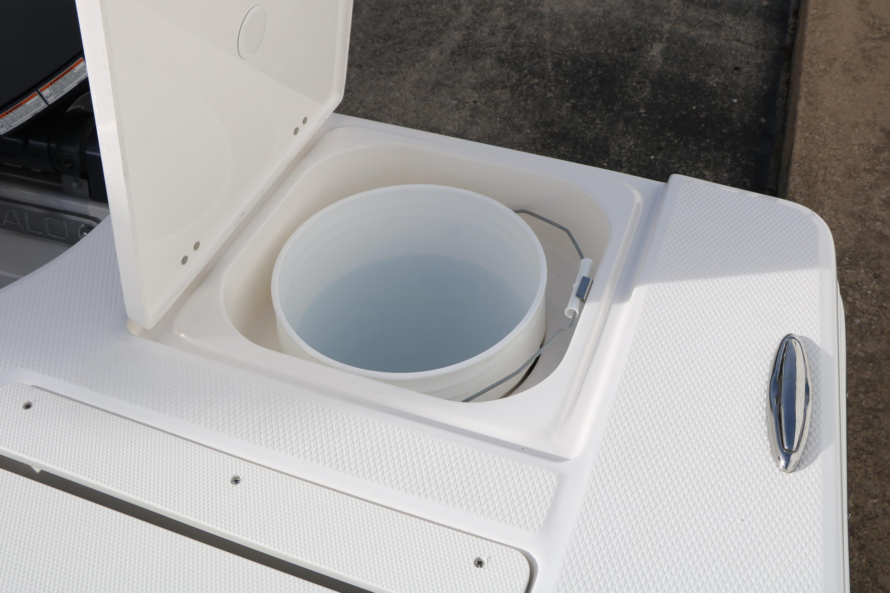 Livewell compartment on 2026 Robalo 206 Cayman boat, featuring a white bucket with water.