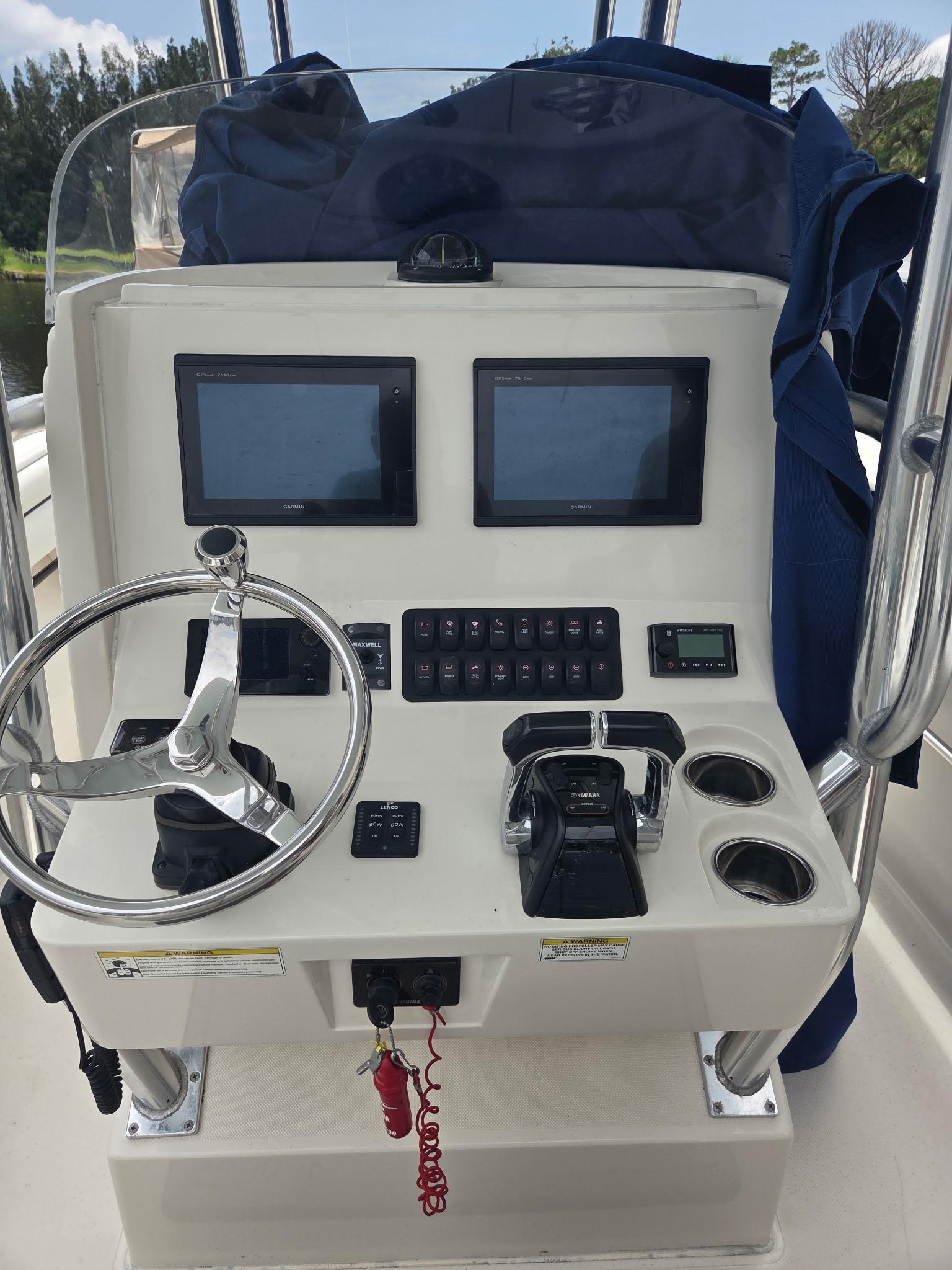 Control panel of a 2015 Jupiter 26 FS boat with dual screens and steering wheel.