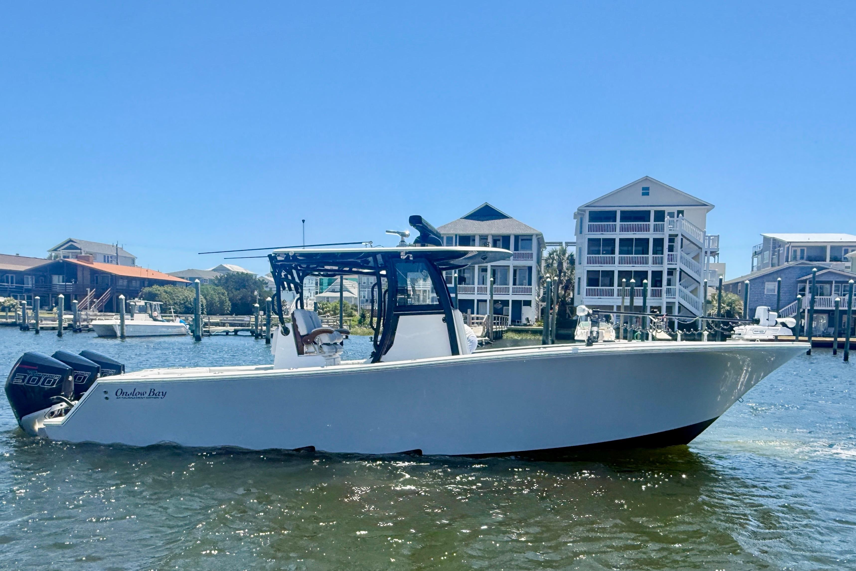 2026 Onslow Bay boat on water near waterfront homes under clear blue sky.