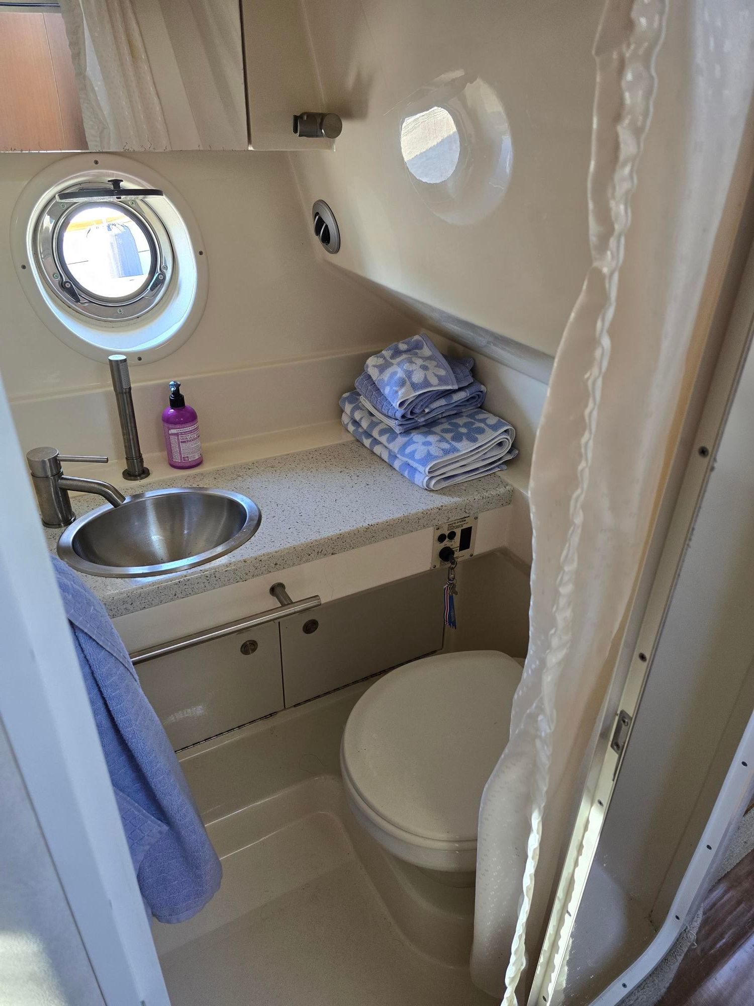 Compact bathroom on a boat with a sink, toilet, and towels.