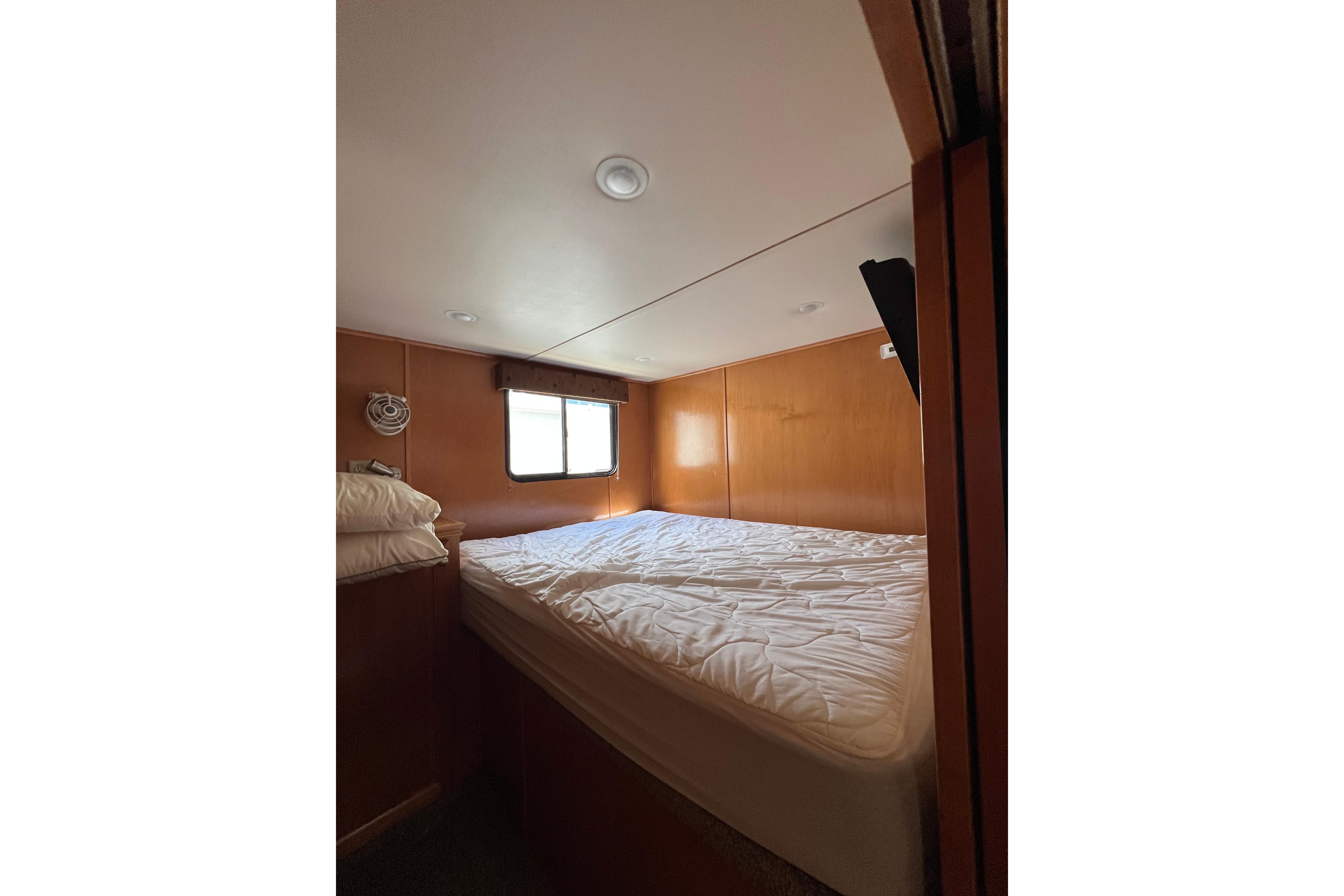 Cozy bedroom interior of 2013 Destination Yacht Lotta Yachta with wooden walls and window.