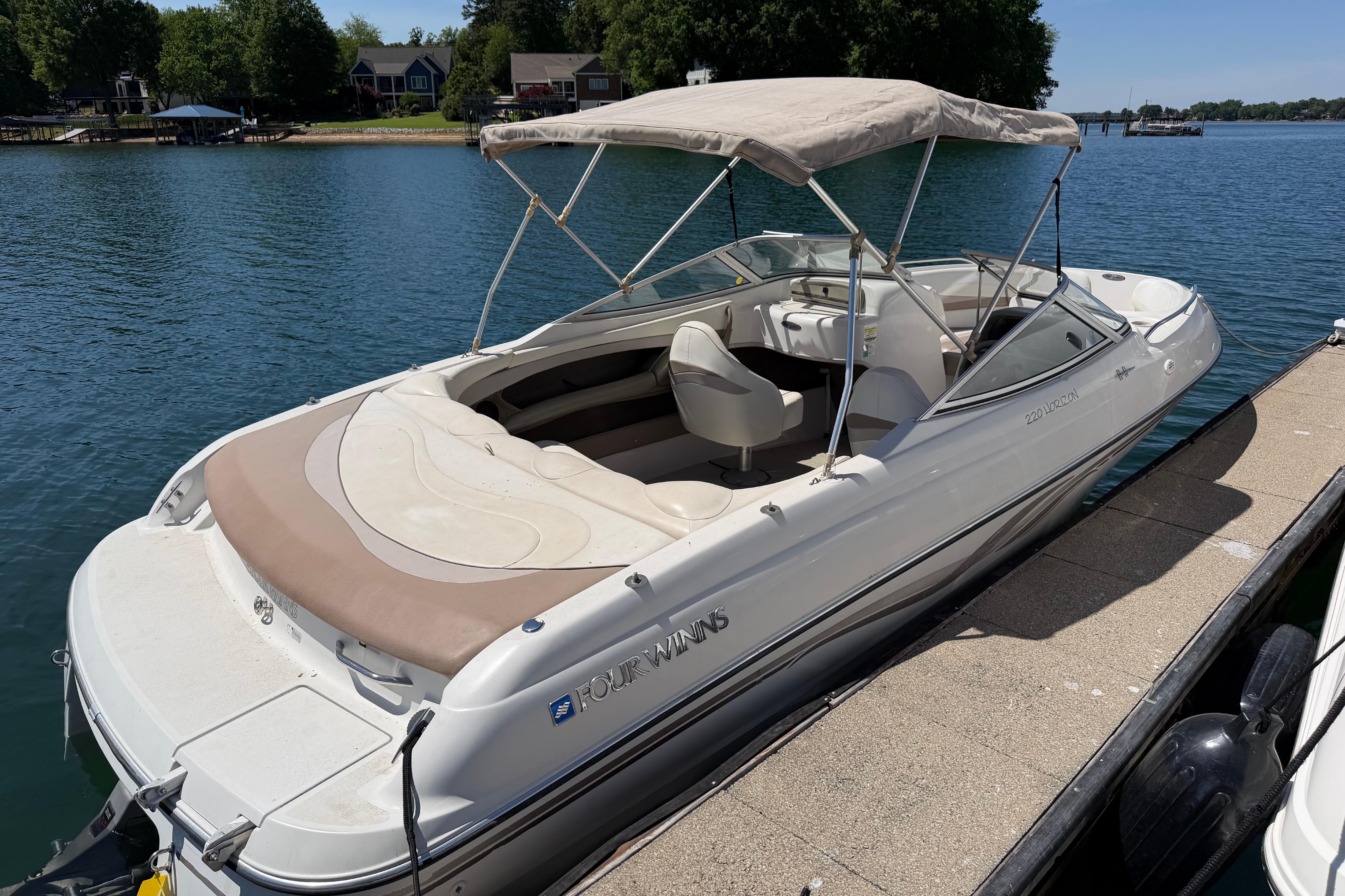 1998 Four Winns 220 Horizon boat docked on a serene lake with canopy.