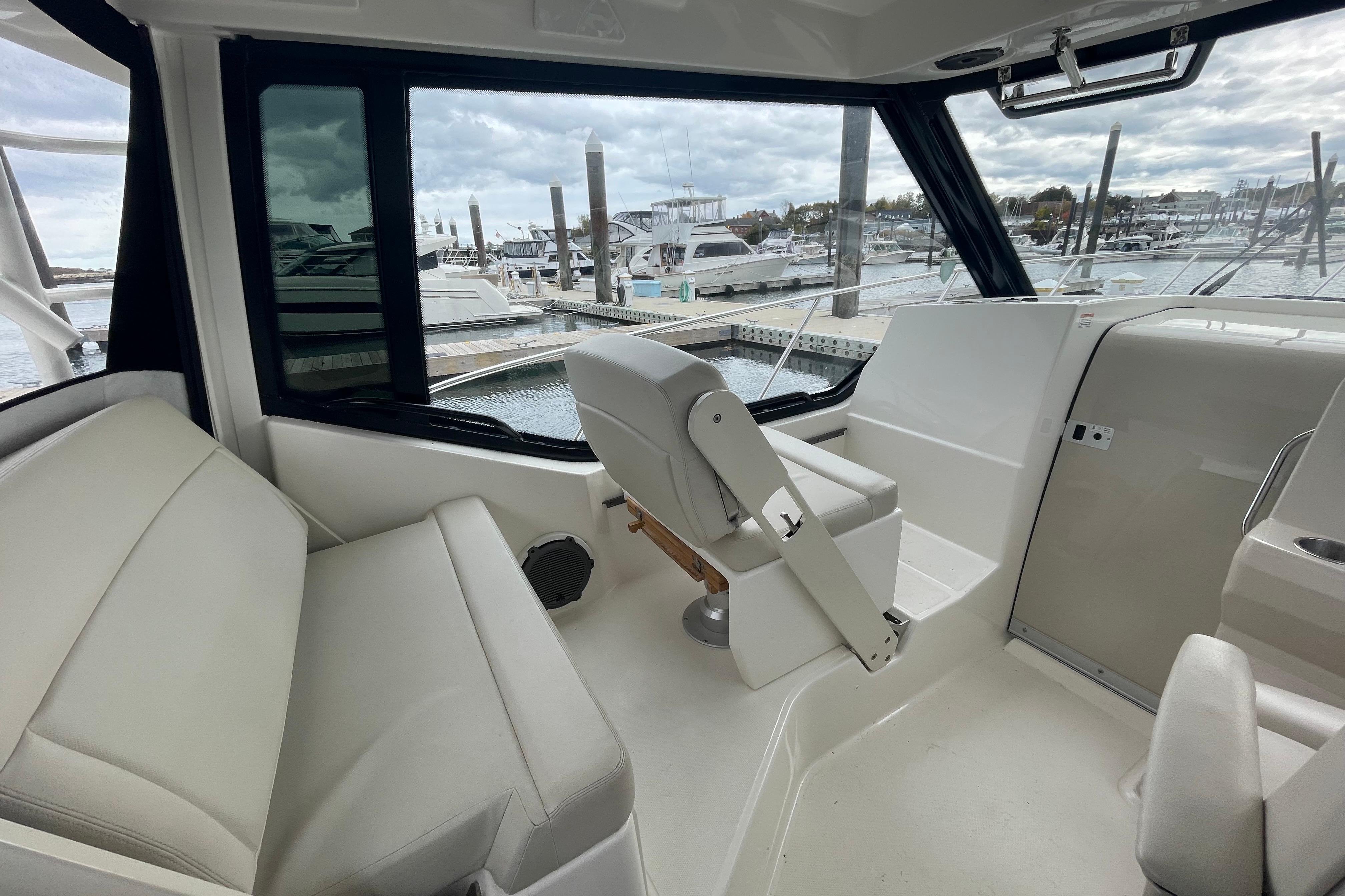 2023 Boston Whaler 325 Conquest interior with seating and helm, docked at marina.