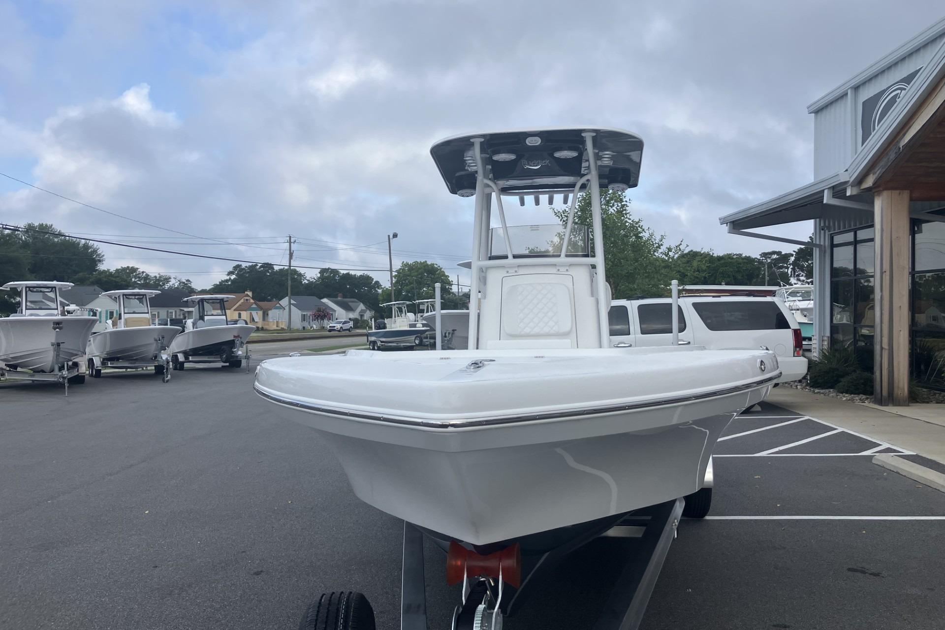 2026 BlackJack 256 Coastal boat on trailer at dealership, overcast sky.