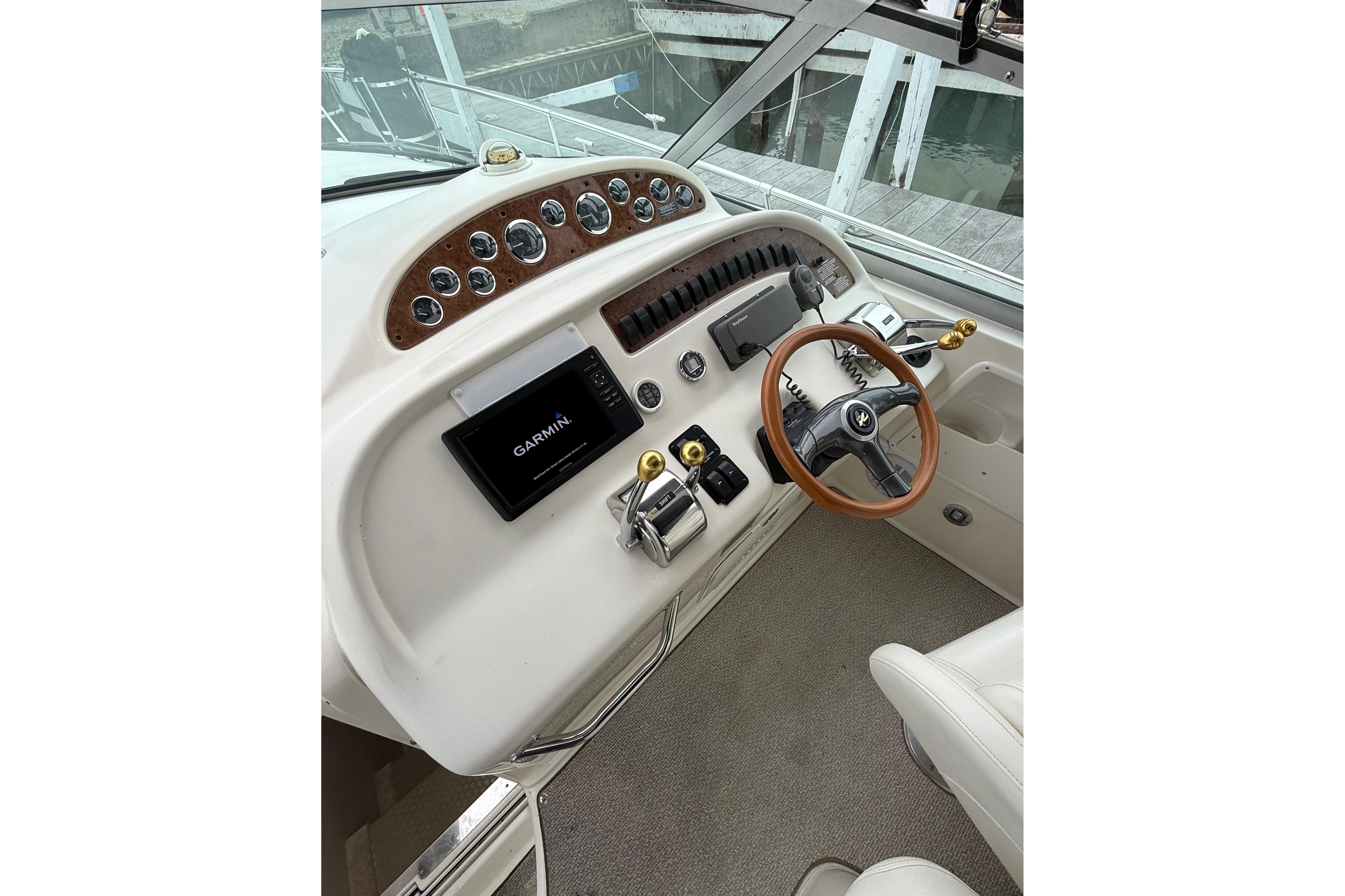1999 Sea Ray Sundancer 310 helm with Garmin navigation and wood-accented steering wheel.