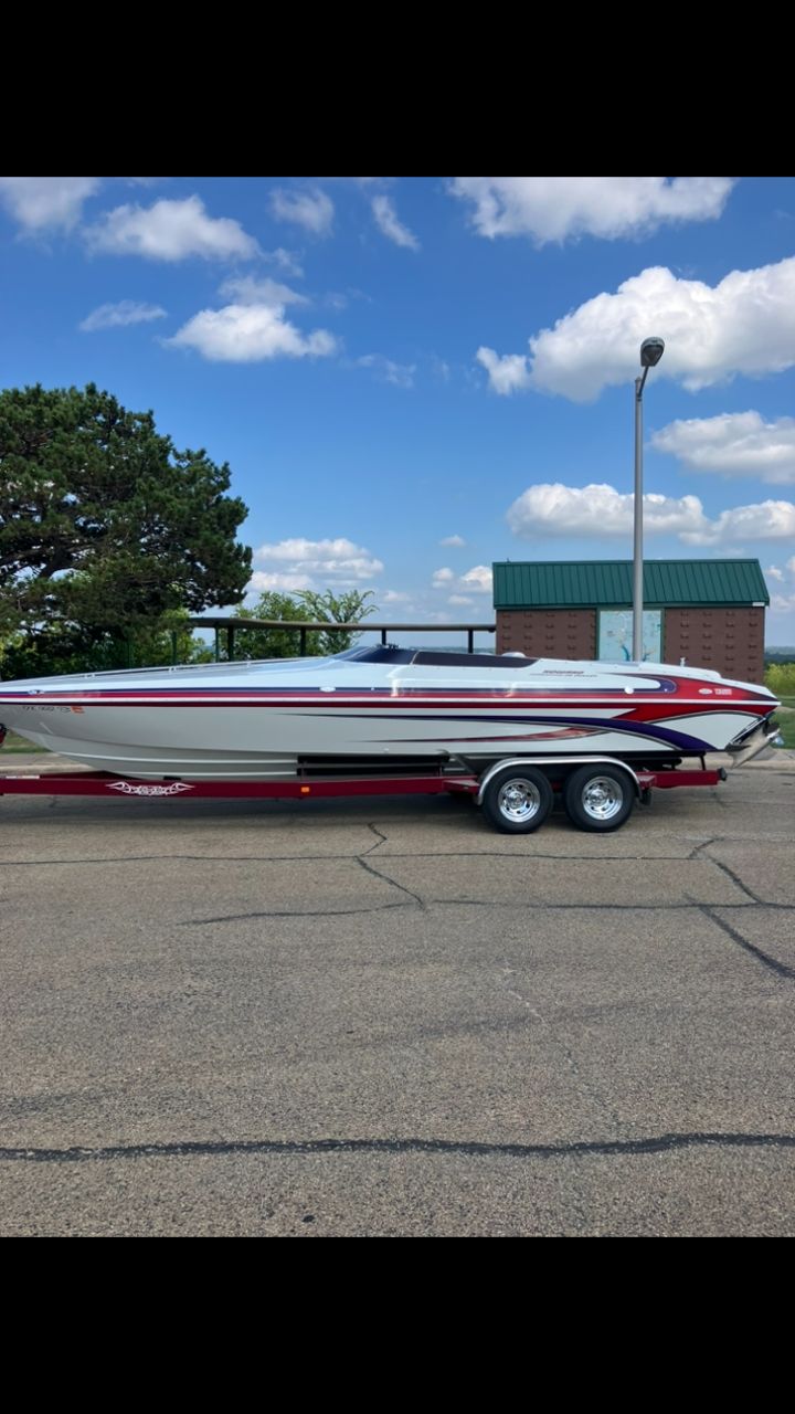 A 2003 Howard Bullet boat on a trailer, parked in a lot under a blue sky.