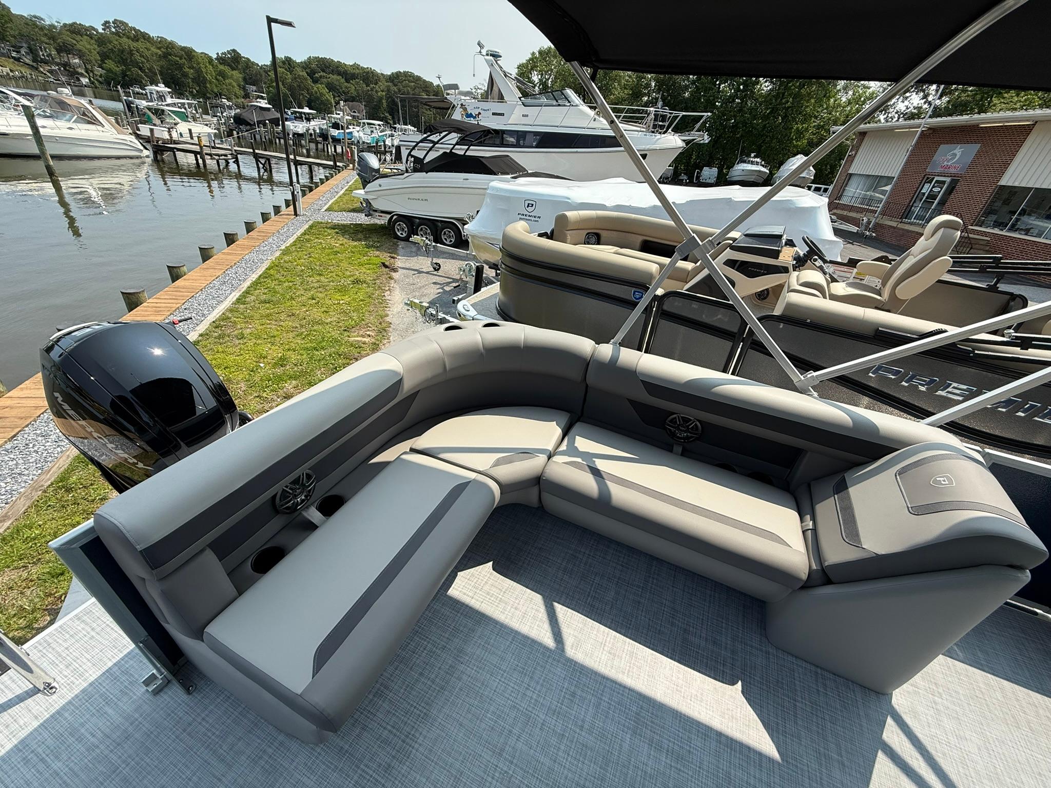 Premier 200 Sunscape RE XLC 2025 pontoon boat with luxurious seating by a marina.