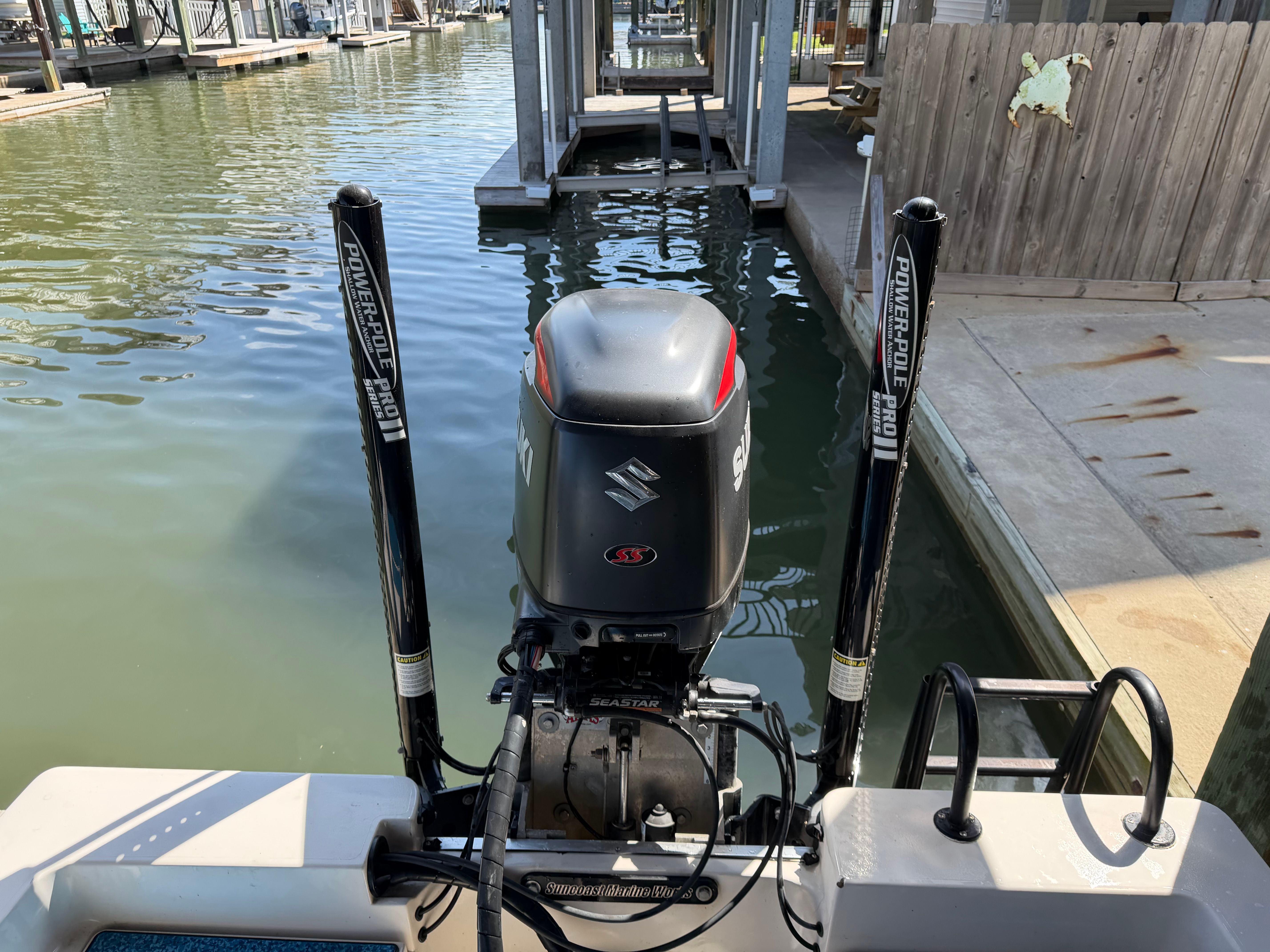 A boat with a Suzuki engine is docked in a calm harbor.