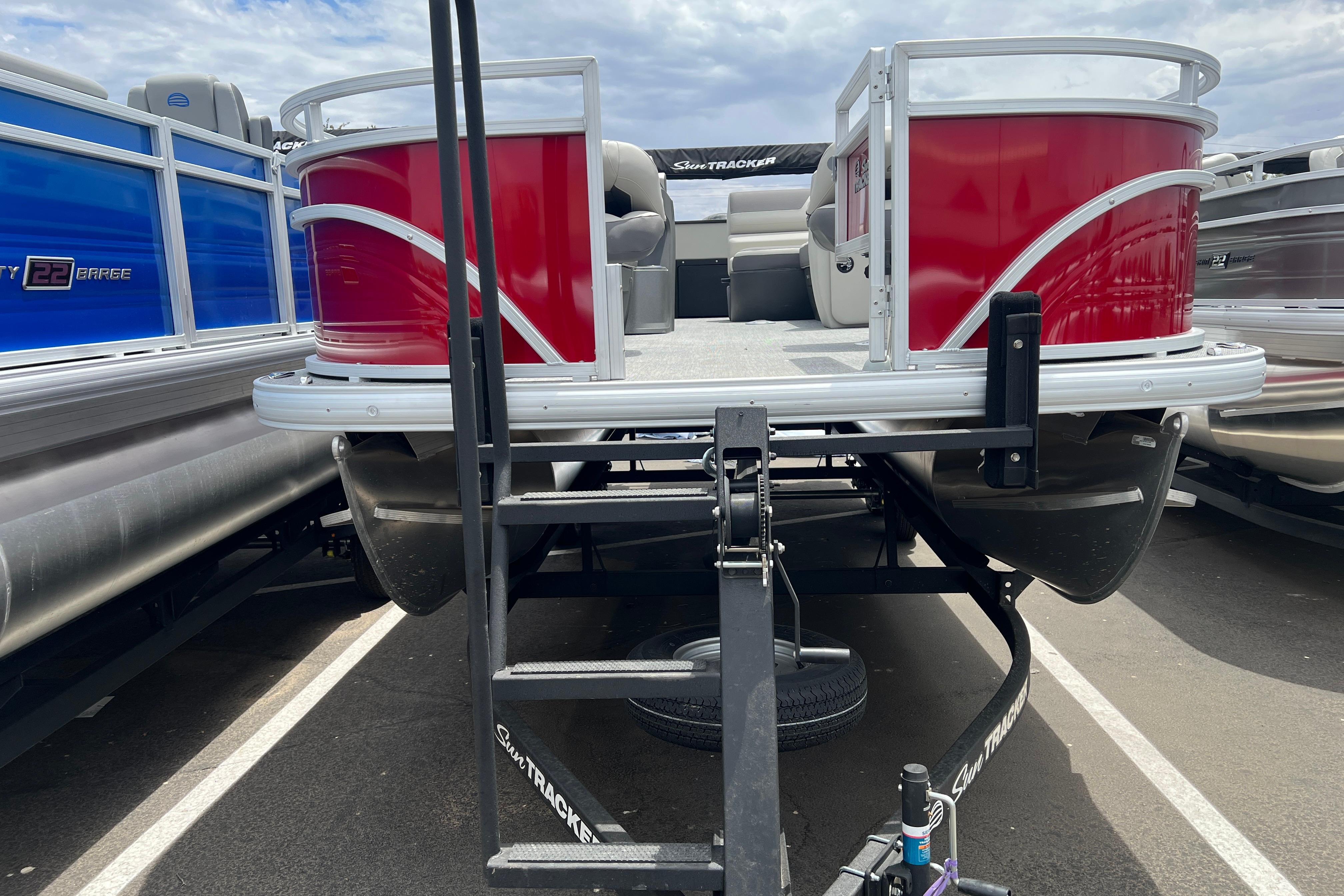 2026 Sun Tracker Fishin' Barge 22 DLX pontoon boat, red and silver, on trailer.
