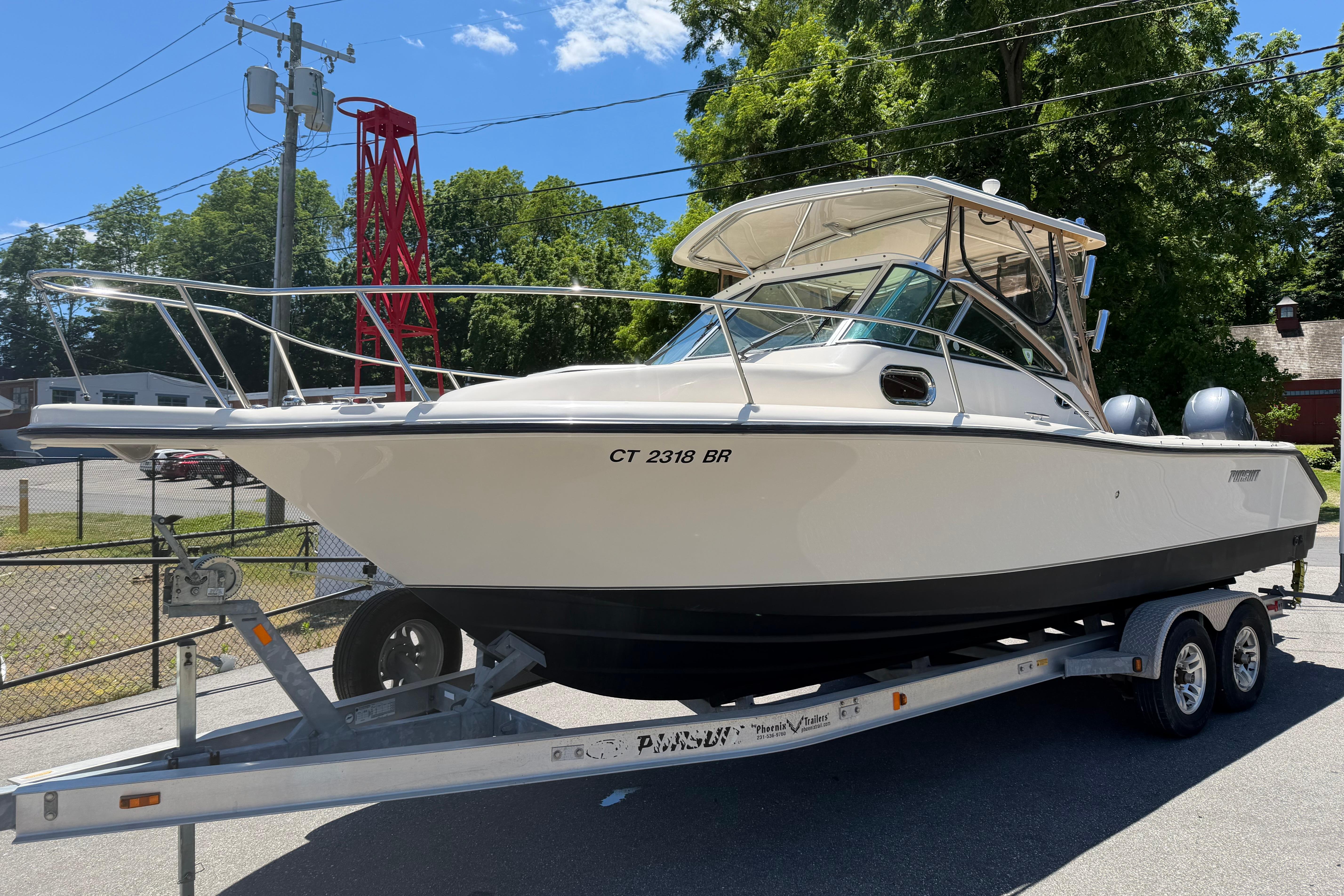 2010 Pursuit OS 255 Offshore boat on trailer, parked outdoors under clear sky.
