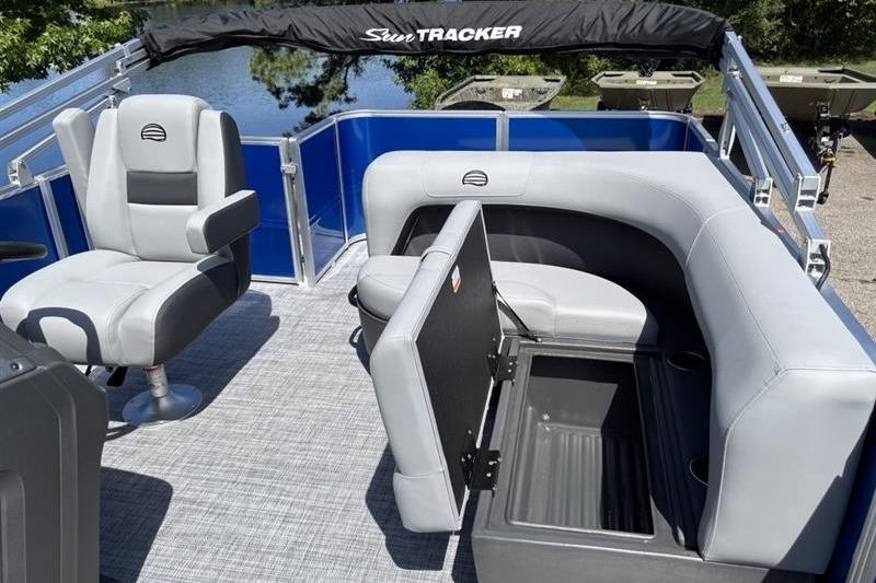 2026 Sun Tracker Party Barge 18 DLX interior with seating and storage, on a sunny day.