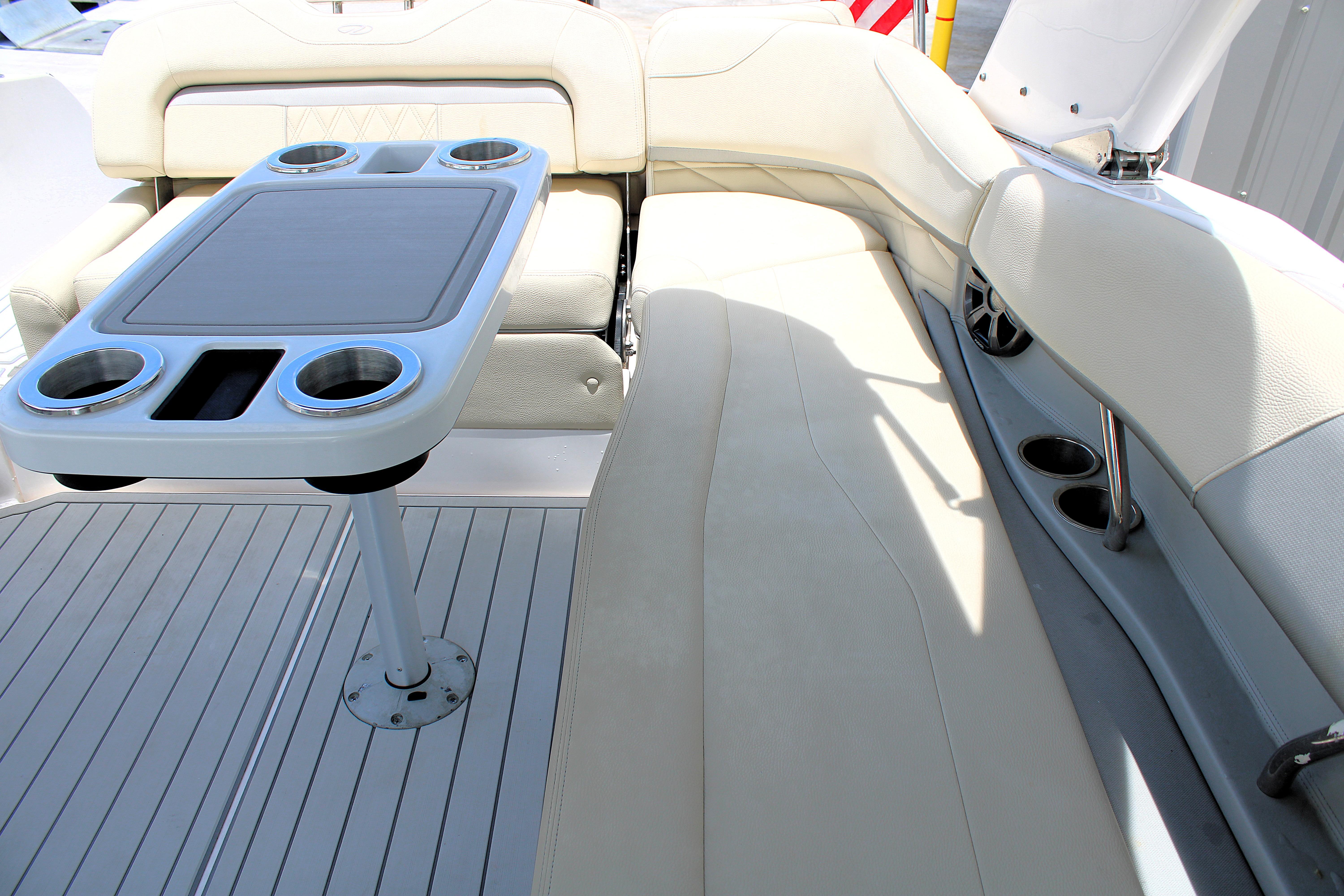 Luxurious seating area on a 2021 Regal 26 OBX boat with cupholders and table.