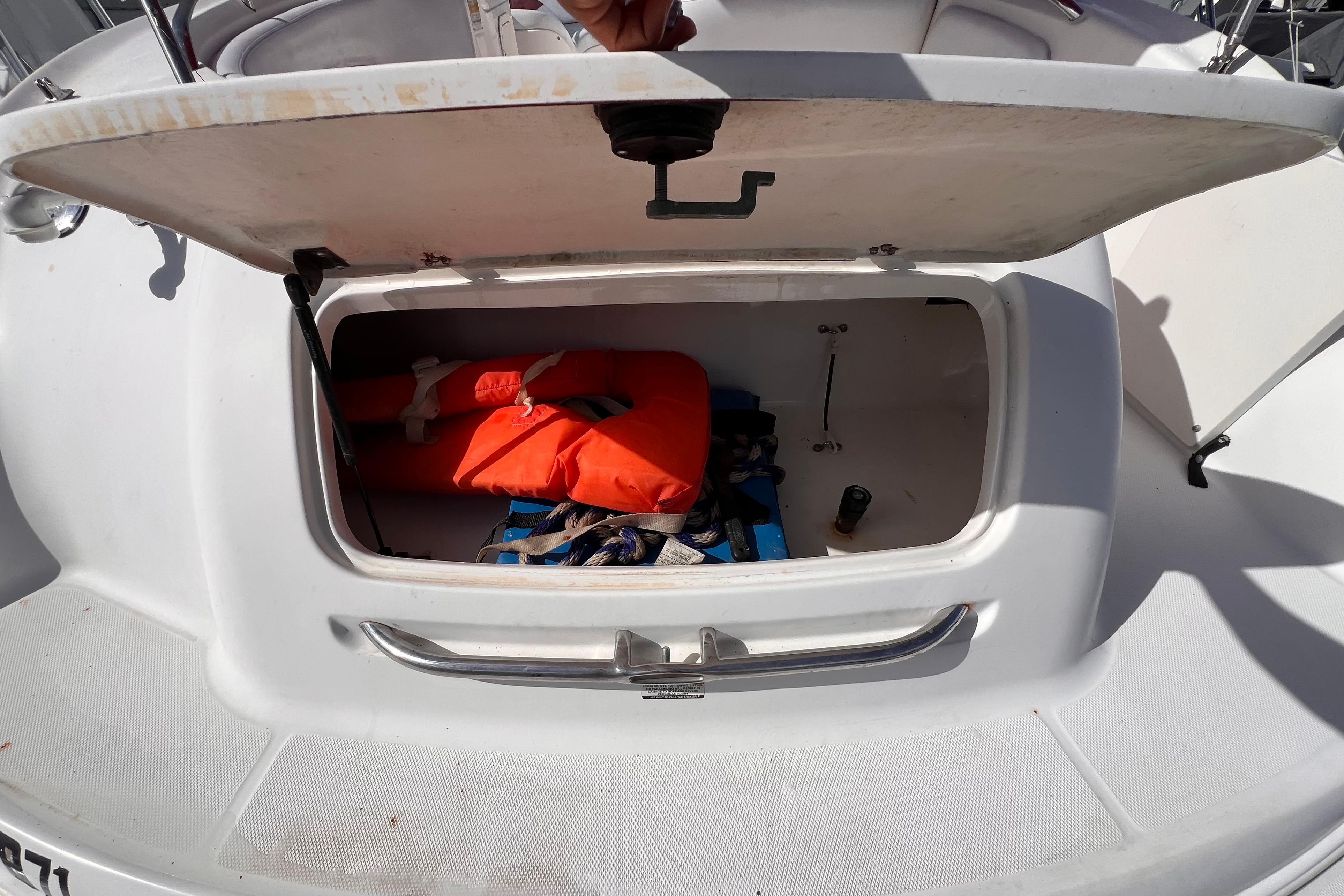 Open storage compartment on 2002 Chaparral 232 Sunesta boat with life jacket inside.