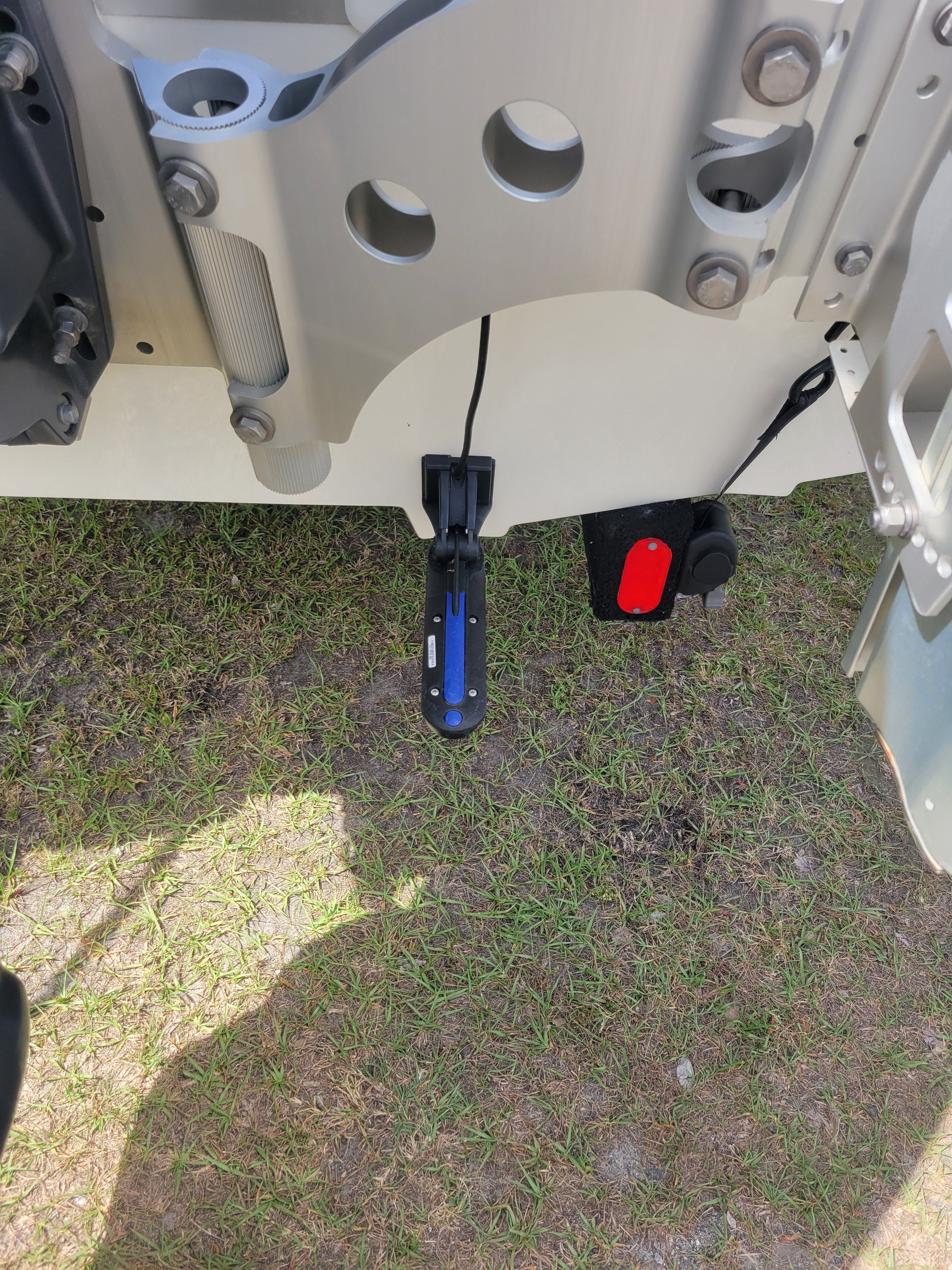 Back of a boat with motor and sensor on grass.