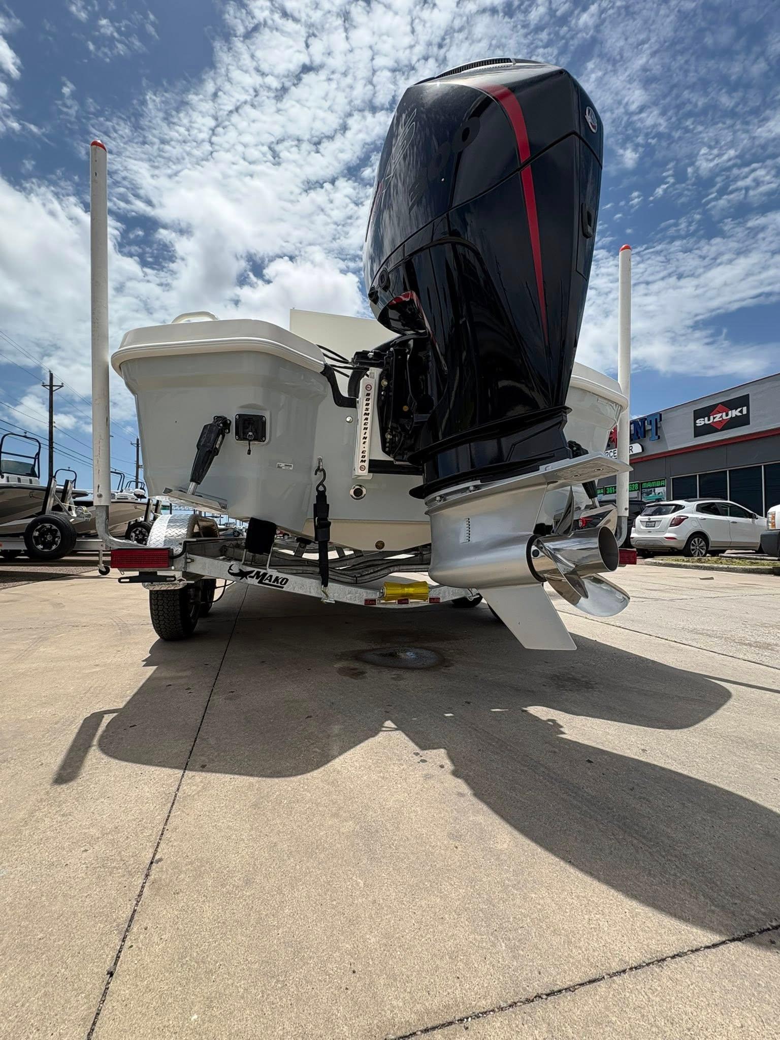 2025 Mako 24 APEX boat with powerful outboard motor, parked outdoors under a cloudy sky.