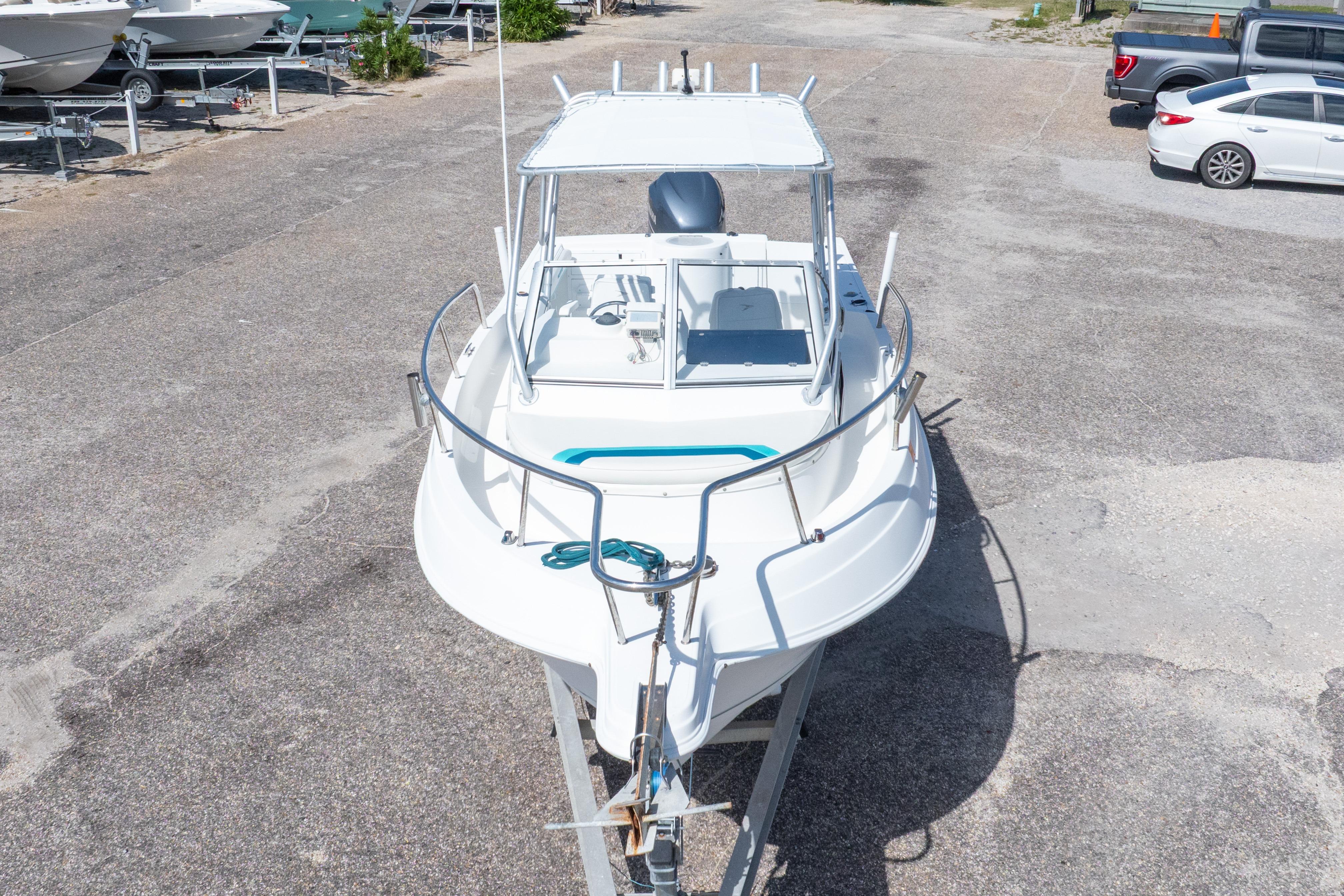 1999 Aquasport 225 Explorer boat on trailer in parking lot.