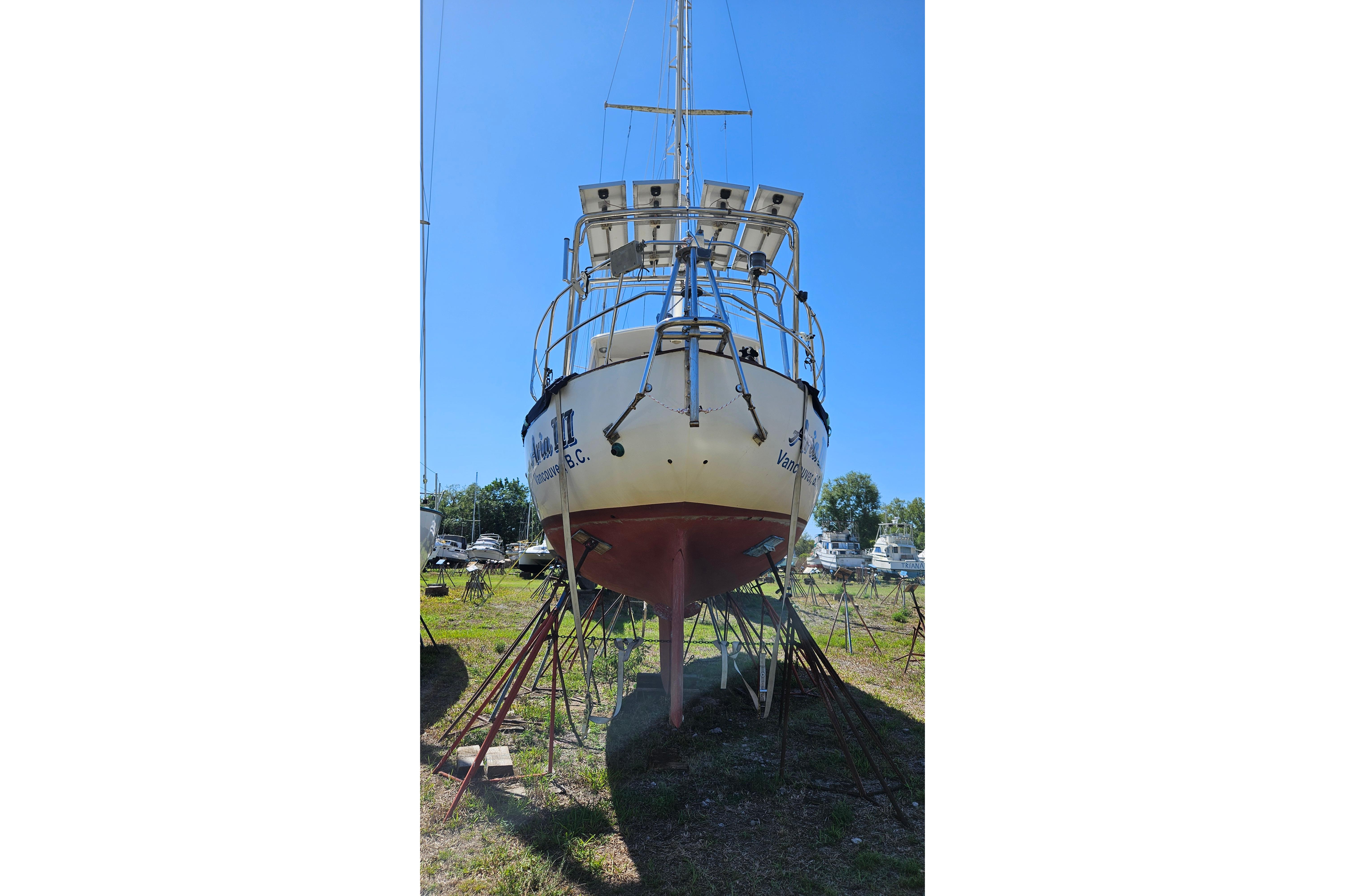 1989 Pacific Seacraft 37 sailboat on stands, viewed from the stern, under clear blue sky.