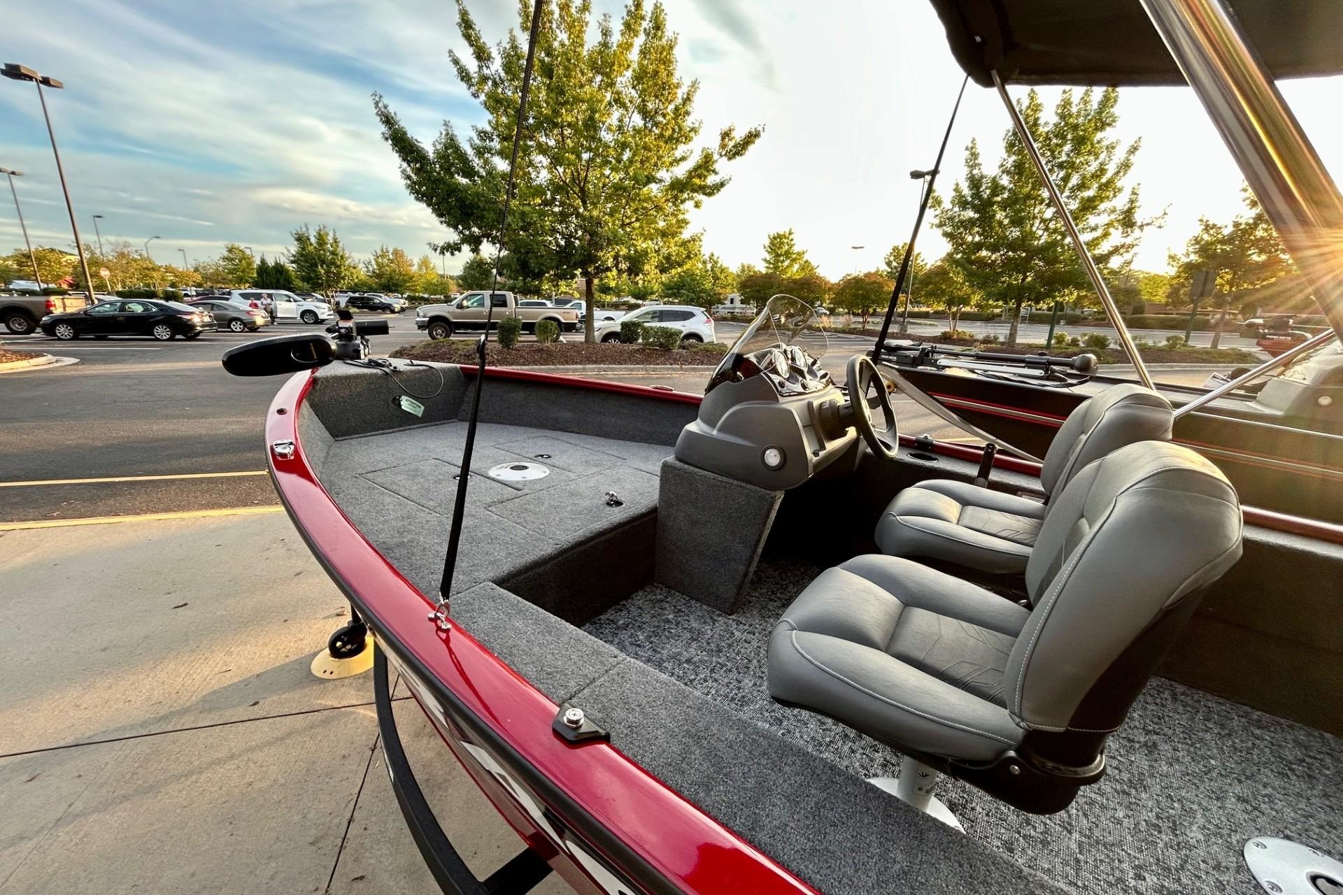 2026 Tracker Super Guide V-16 SC boat with gray seats and red exterior in a parking lot.