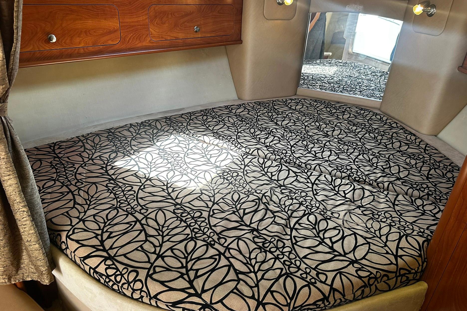 Interior cabin of 2012 Rinker 310 Express Cruiser LE with patterned bedding and wood accents.