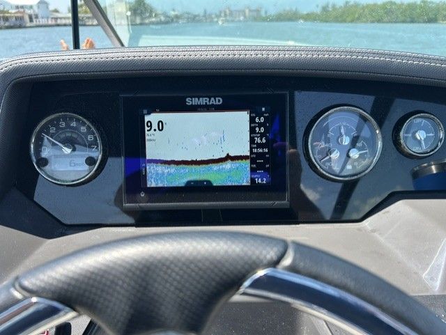 The dashboard of a boat with a Simrad screen and various gauges.