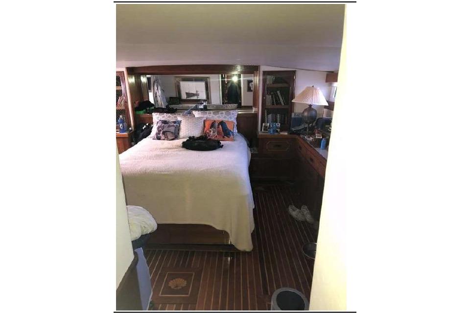 1974 Pacemaker Cockpit Motoryacht bedroom with cozy bed, wooden interior, and decorative pillows.