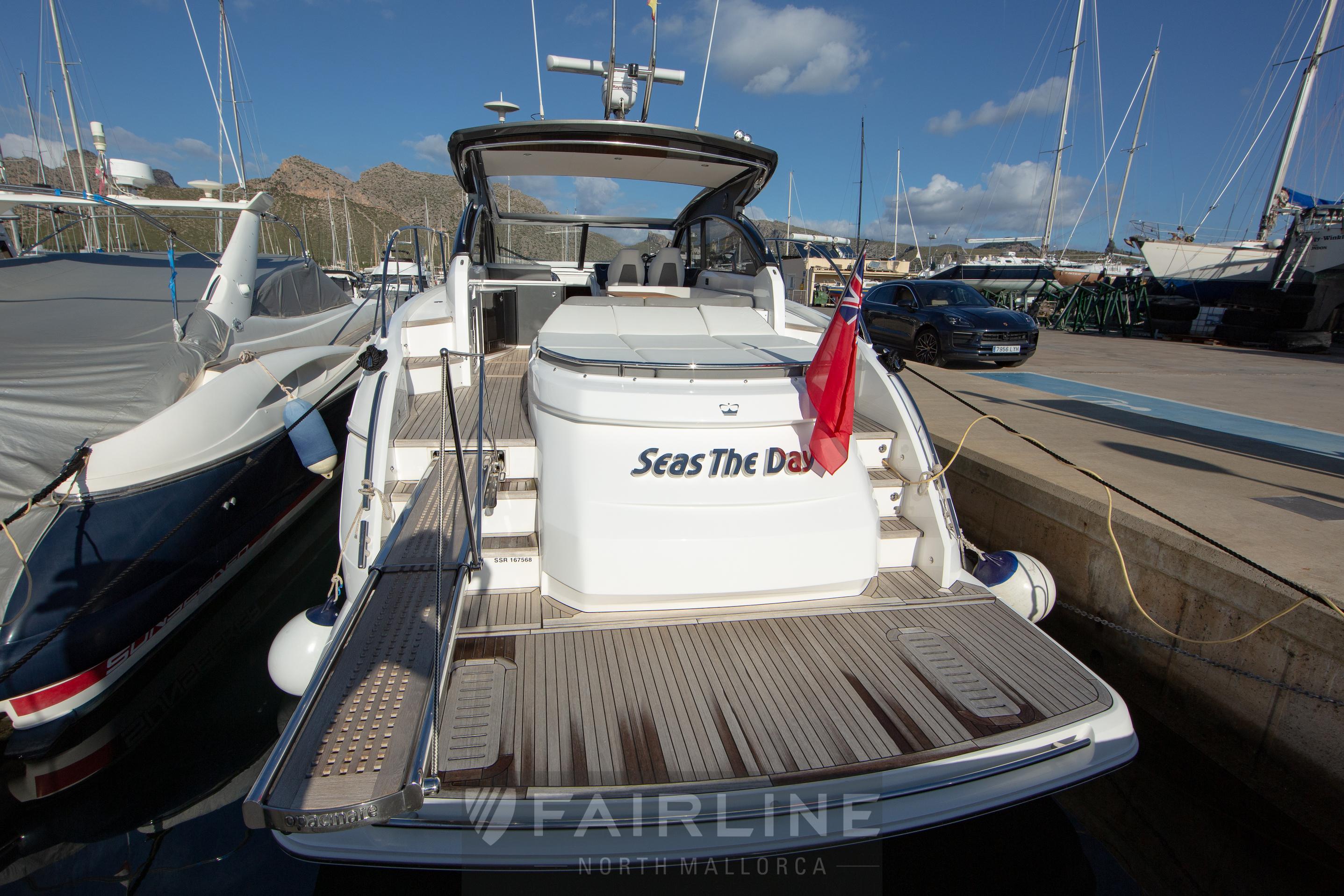 2017 Princess V48 Open yacht docked, rear view with "Seas The Day" text.
