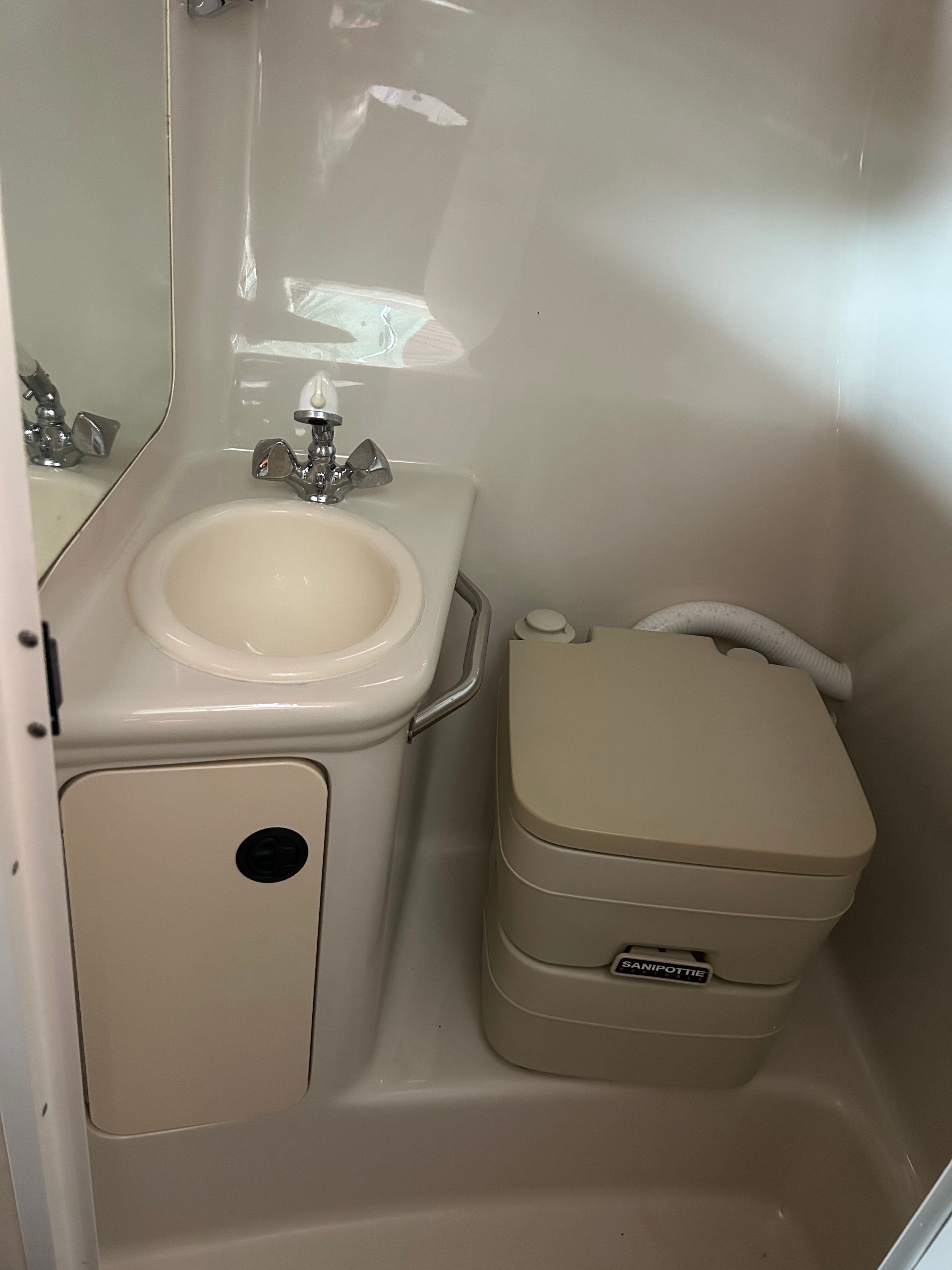 Compact bathroom in 2003 Sea Ray 240 Sundancer boat with sink and portable toilet.