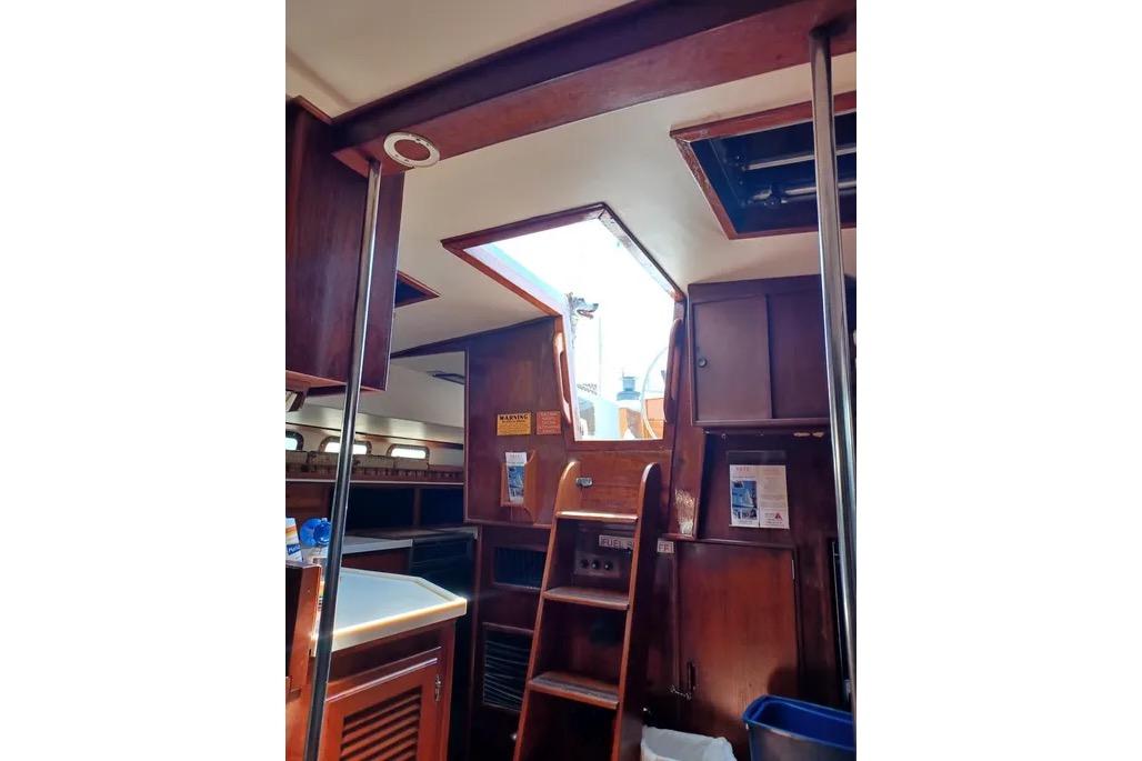 Interior of 1977 Morgan Out Island 51 sailboat with wooden cabinetry and ladder.