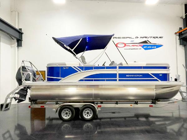 2025 Bennington 20S pontoon boat with blue canopy on trailer in showroom.