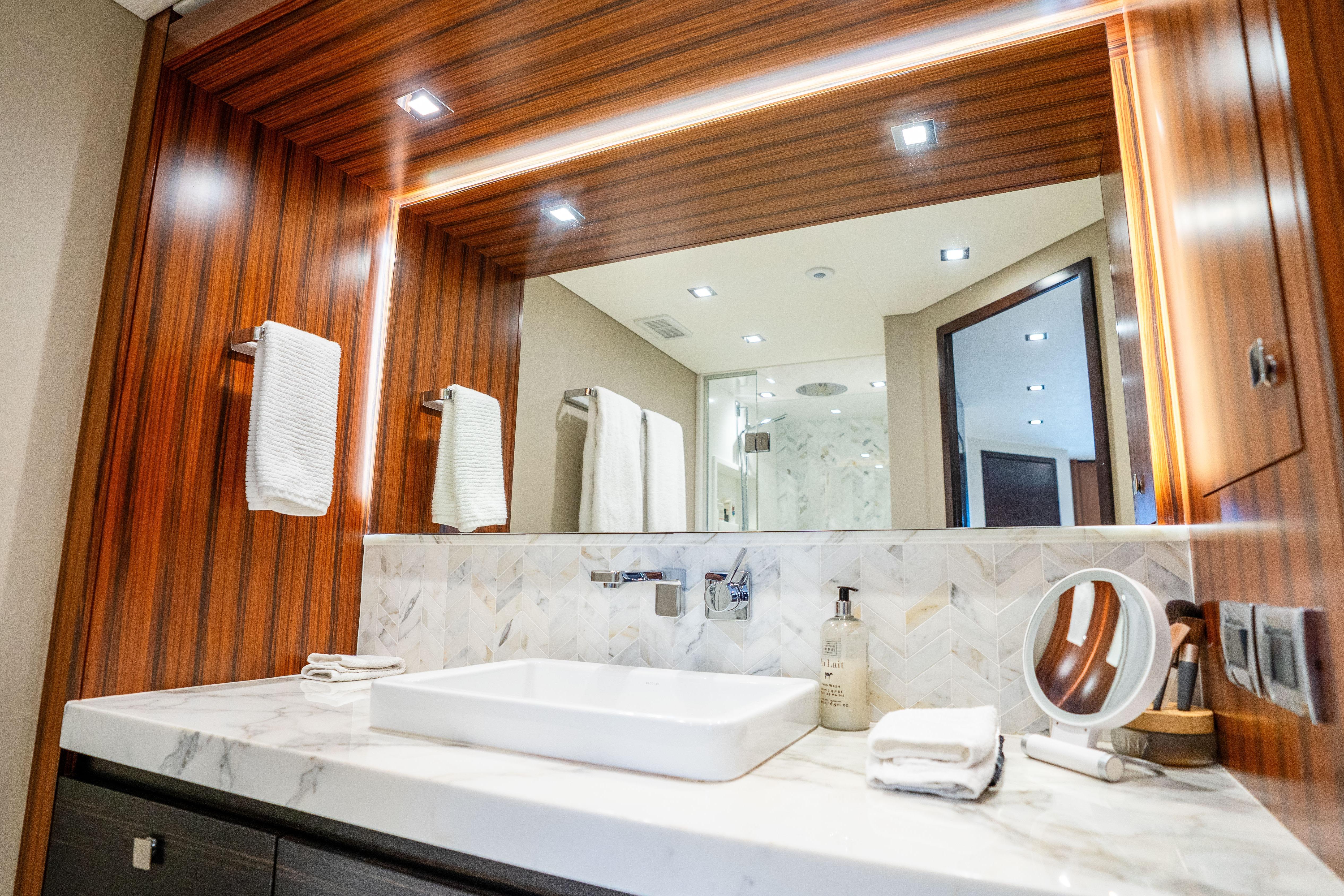 Luxurious bathroom interior of 2021 Hatteras M75 Panacera yacht with elegant wood and marble finishes.