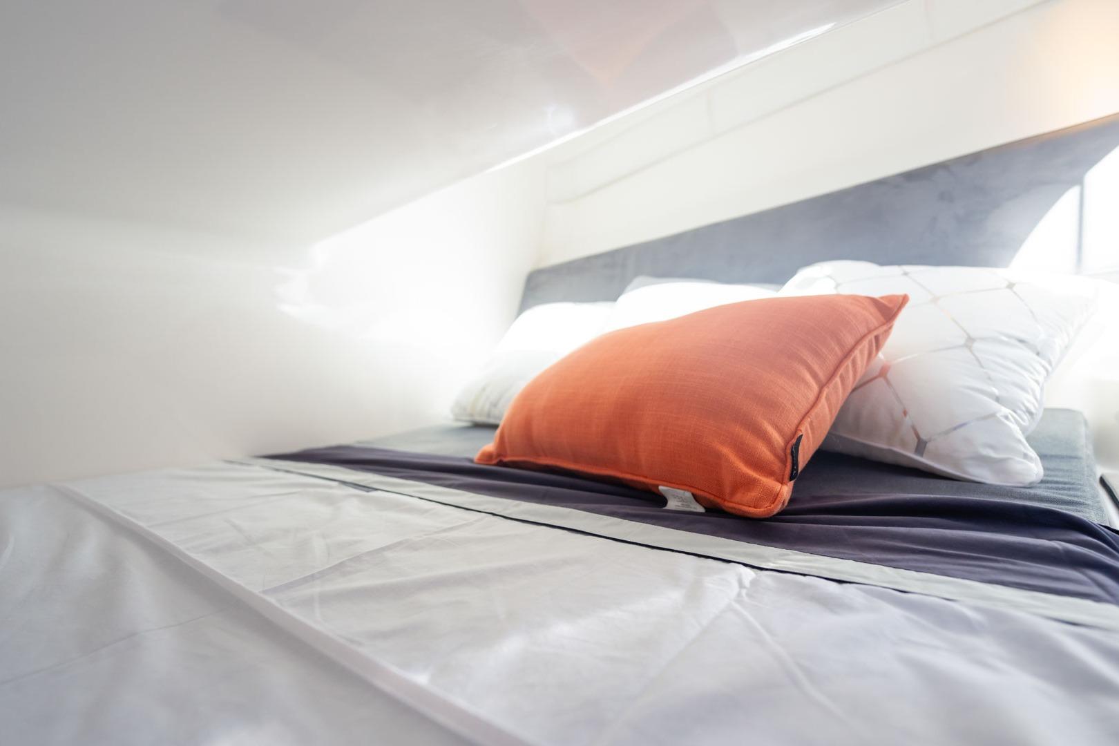 Modern bed with orange and white pillows in a Hanover 305, 2026 model.