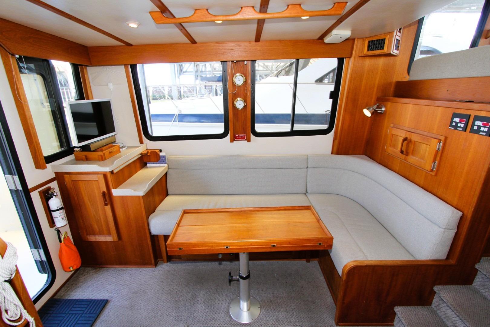 Cozy interior of 2002 Nordic Tug 37 with wooden furnishings and a corner seating area.
