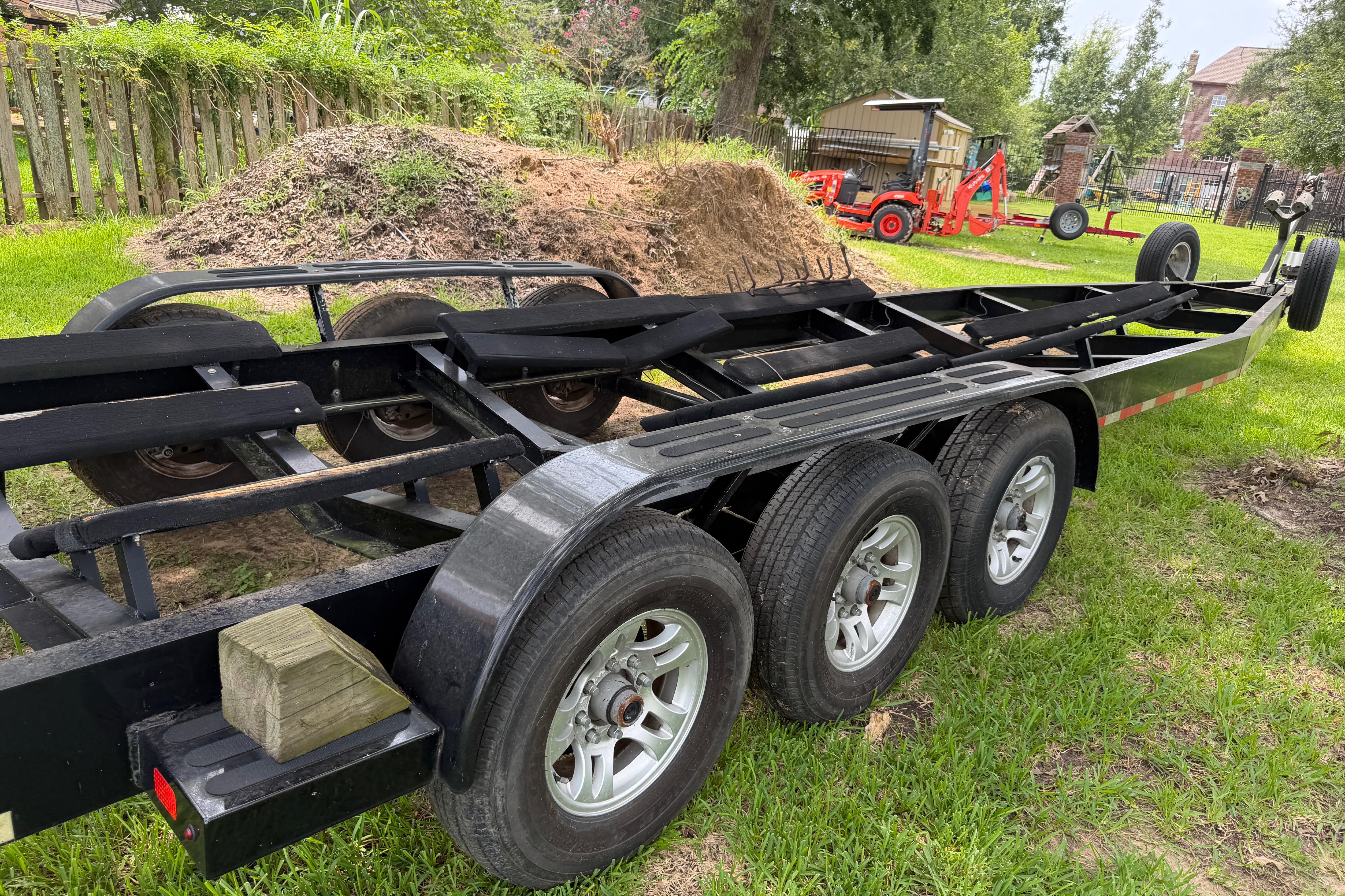 Triple-axle trailer for 2013 Nor-Tech 477 SPX Vee Bottom, parked on grass.