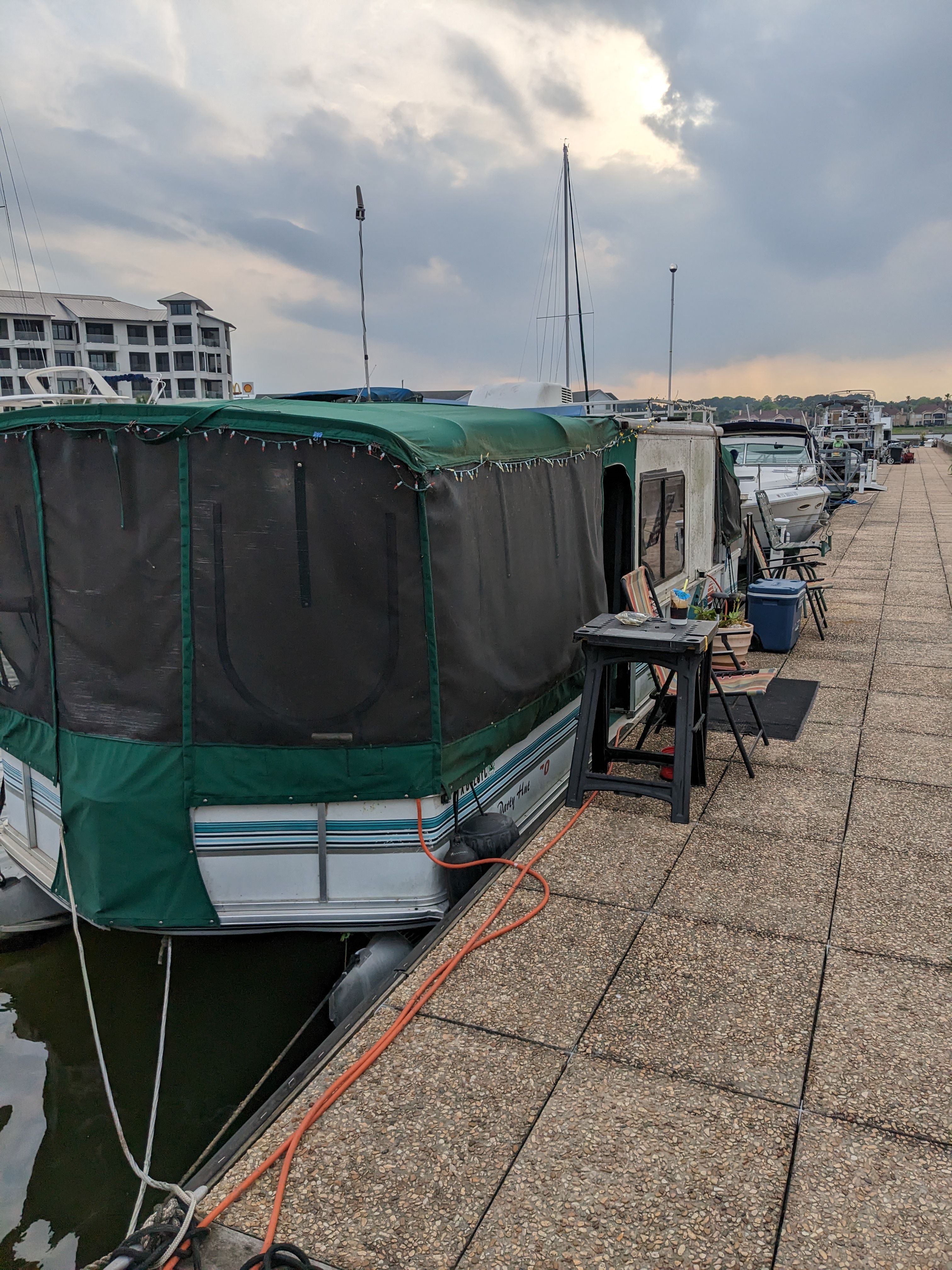 A boat with a green canopy docked at a pier, surrounded by other boats.