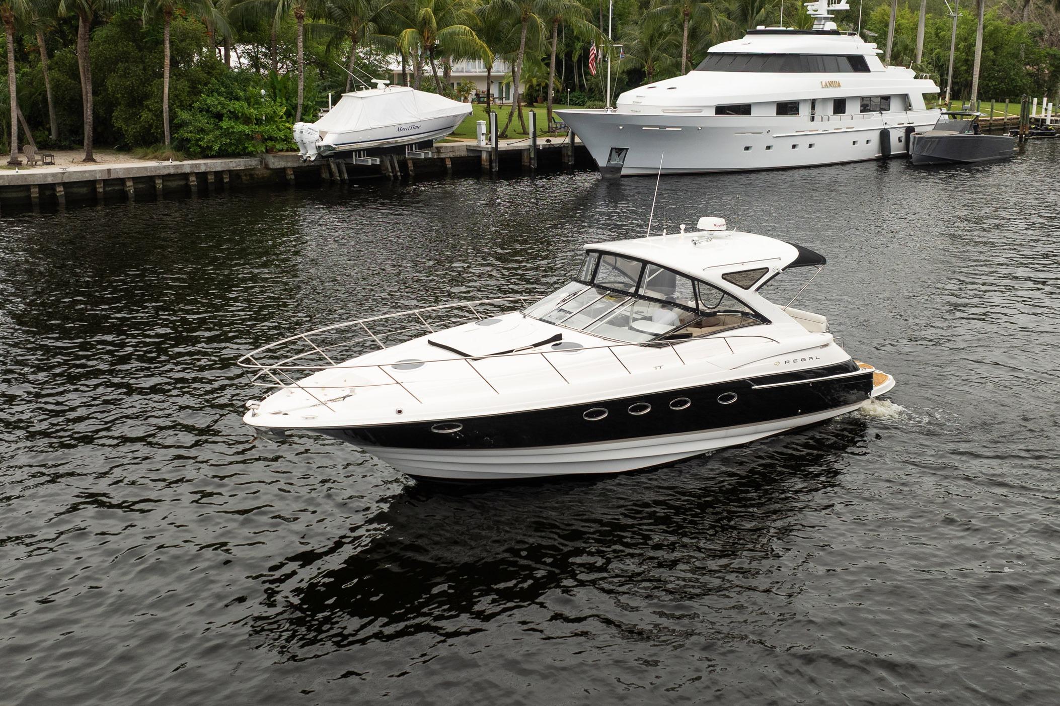2008 Regal Commodore 4460 yacht cruising on a serene waterway with palm trees in the background.