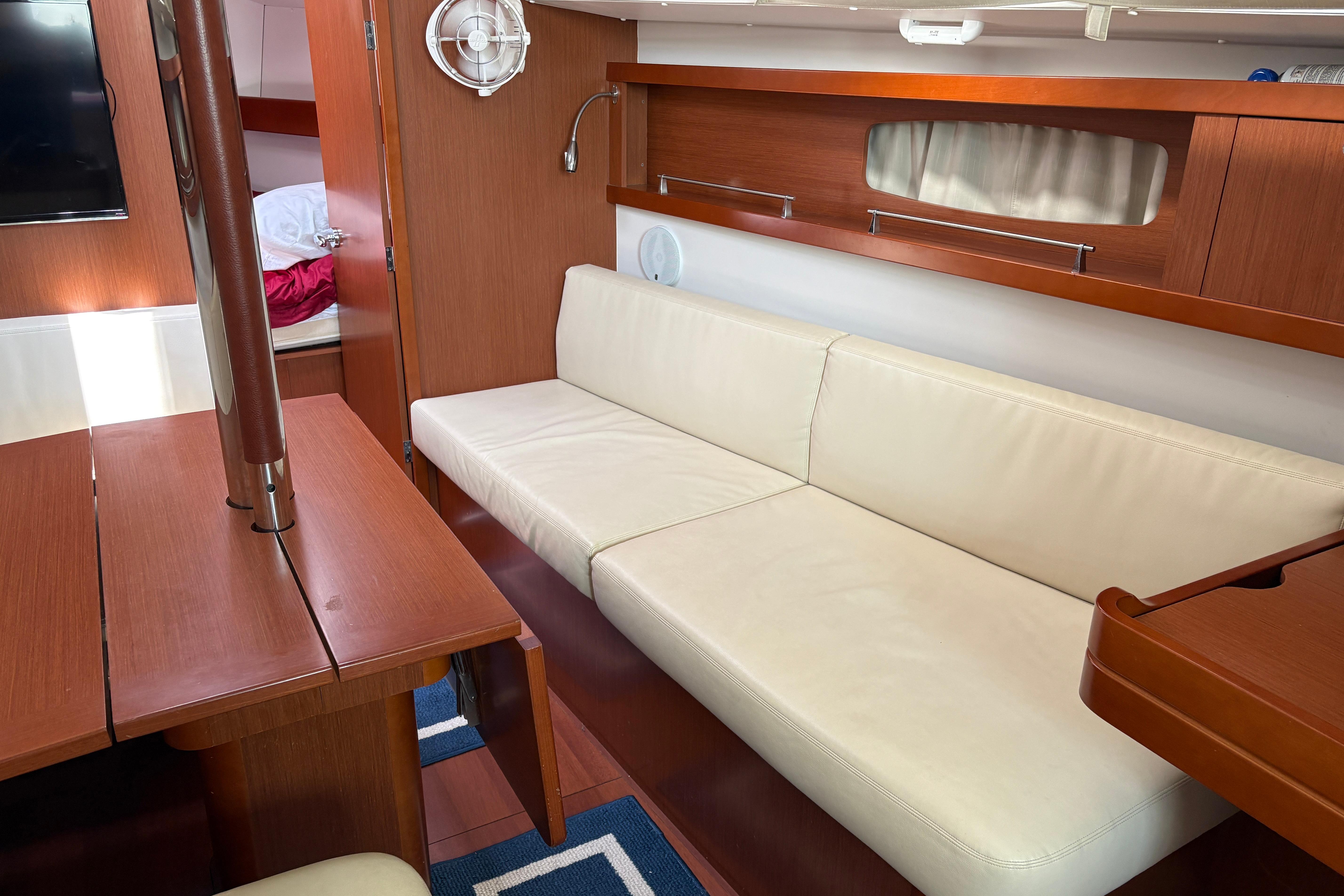 Interior of 2015 Beneteau Oceanis 34 yacht with white sofa and wooden finishes.