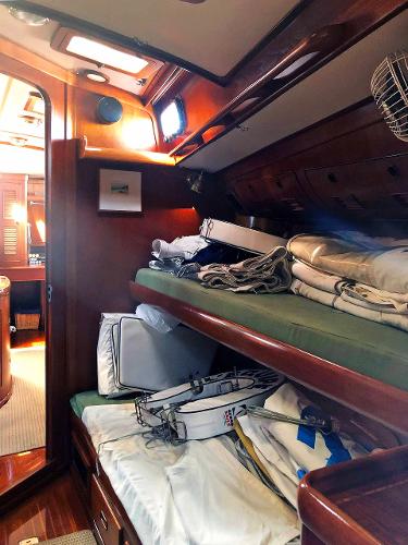 Interior of a 1988 Little Harbor 53 with wood paneling and stacked sails.