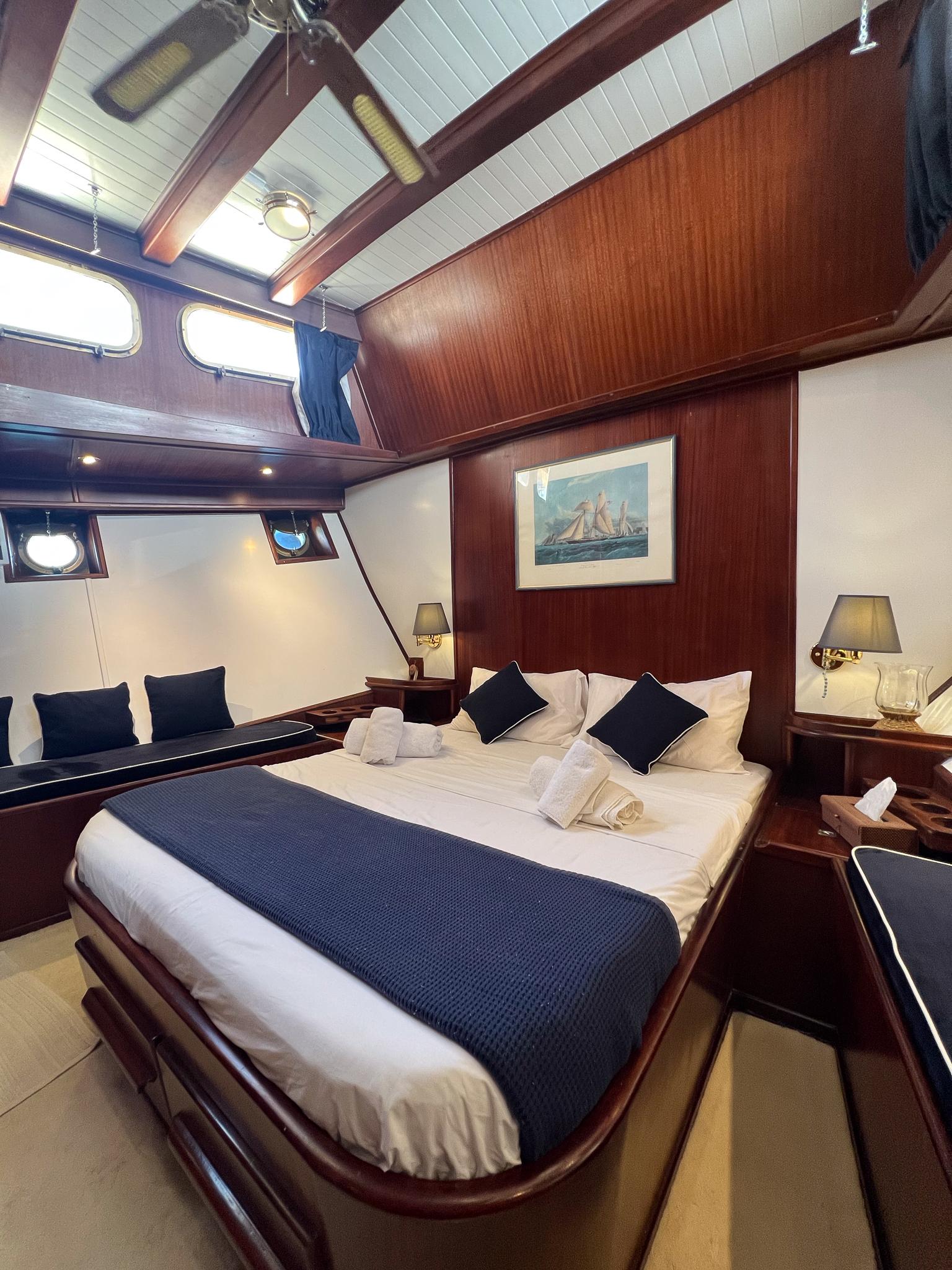 Luxurious 1969 Psarros Shipyard cabin with elegant wood paneling and cozy bedding.