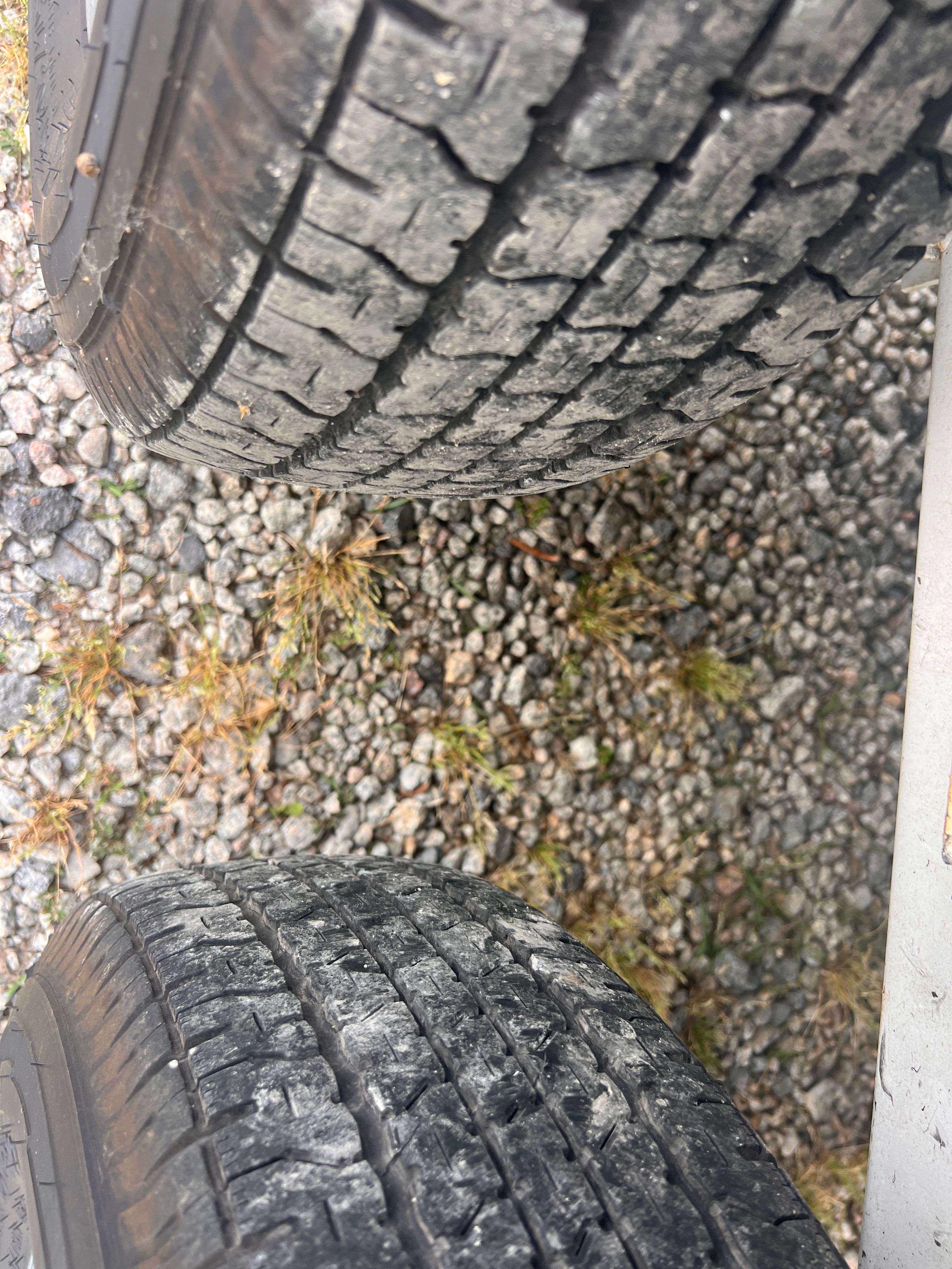 Close-up of two tires on a gravel surface.