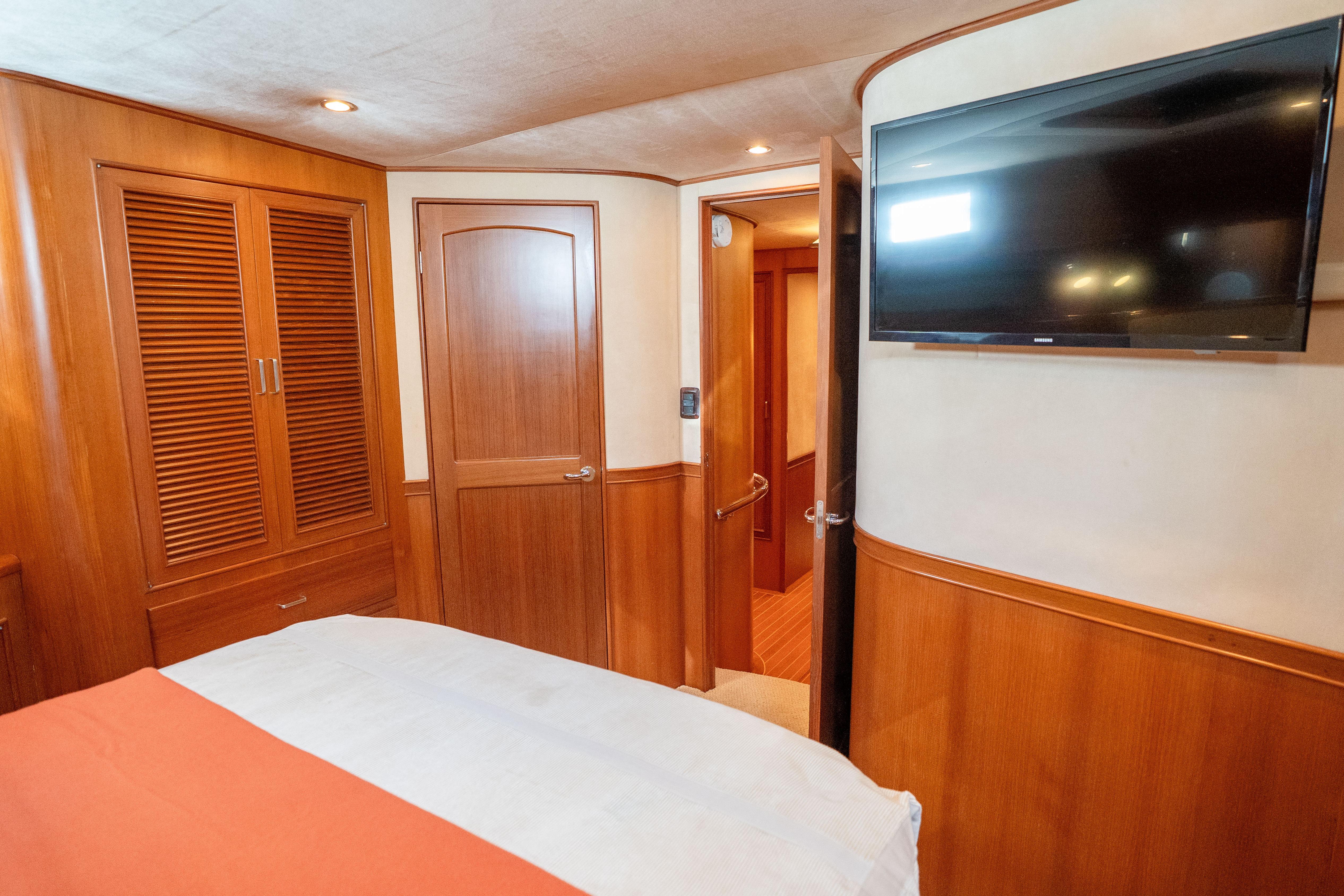 Luxurious cabin interior of a 2006 Fleming 75 yacht with wood paneling and mounted TV.