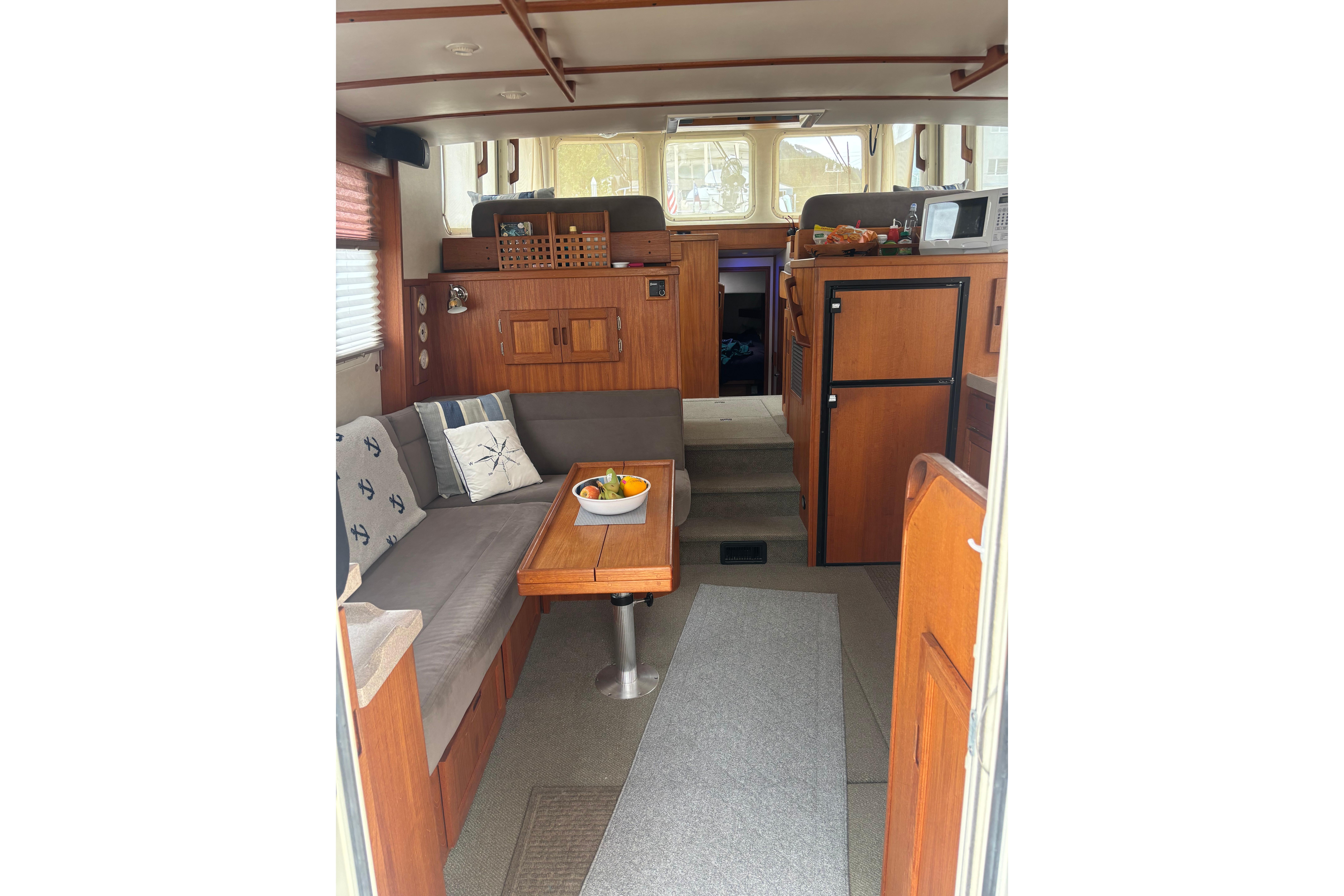 Cozy interior of a 2004 Nordic Tug 37 with wooden furnishings and seating area.