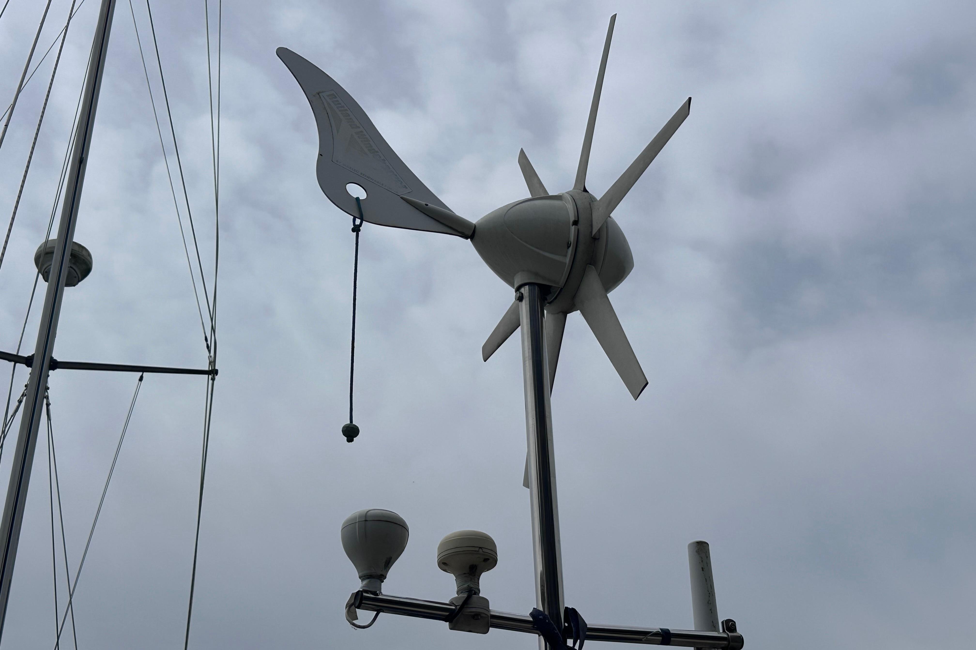 Wind turbine on a 1999 Hallberg-Rassy 39 sailboat against a cloudy sky.
