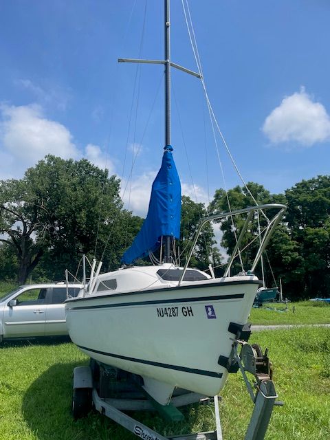 A 1986 Wellcraft Starwind 19 sailboat on a trailer in a grassy area.