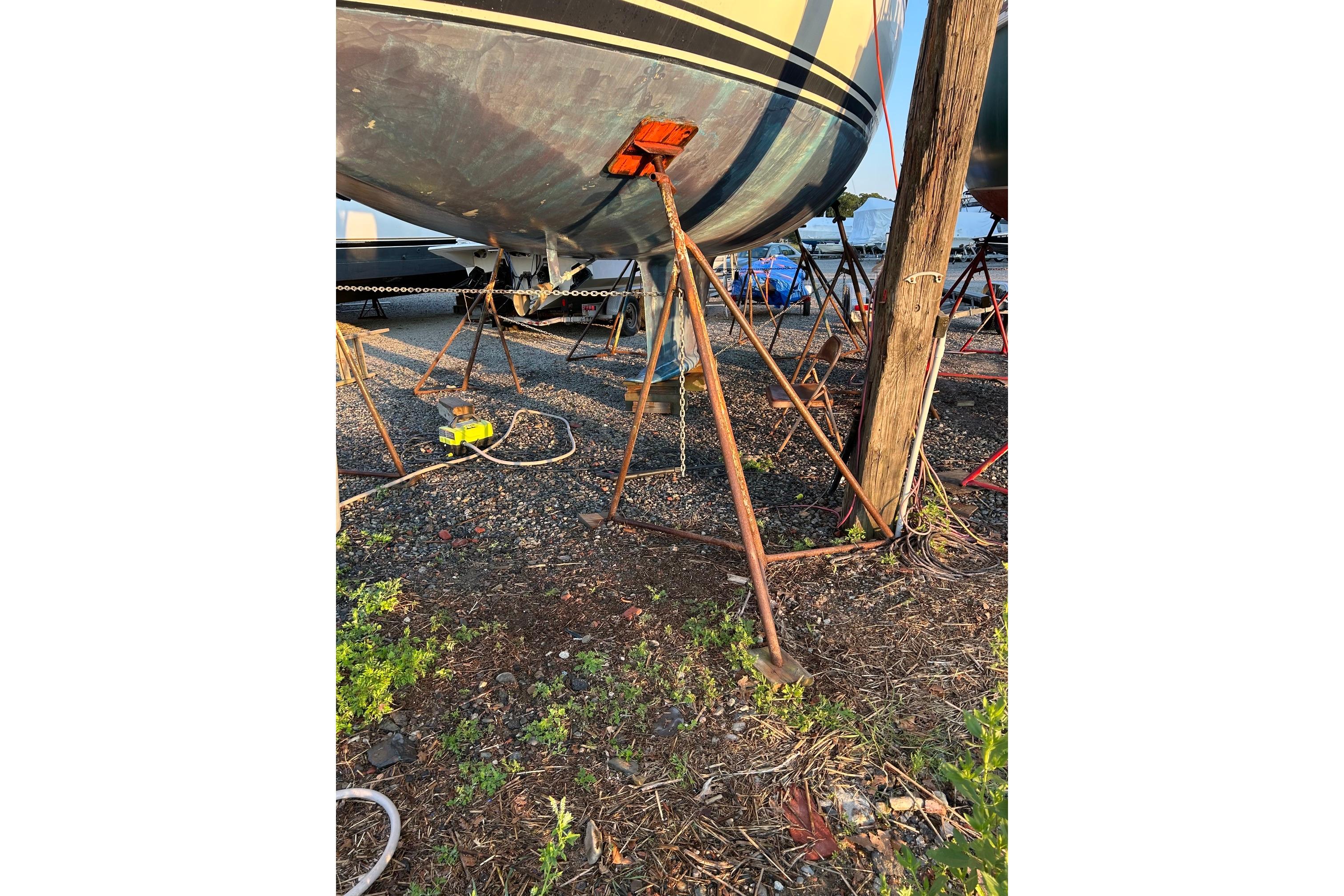 1987 Ericson 38-200 sailboat on stands in a boatyard, surrounded by equipment.