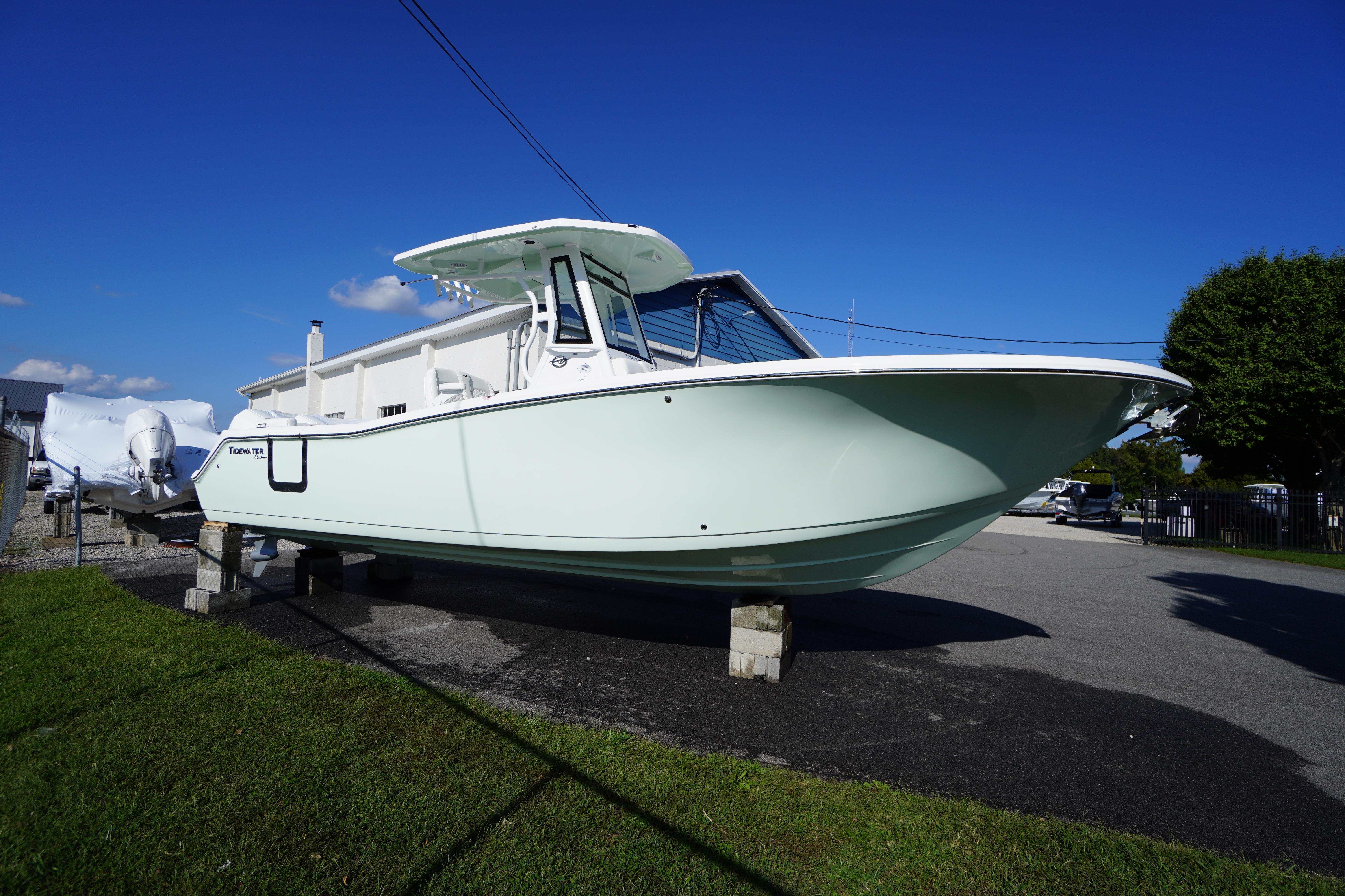 2026 Tidewater 272 LXF boat on display, elevated on blocks, under clear blue sky.