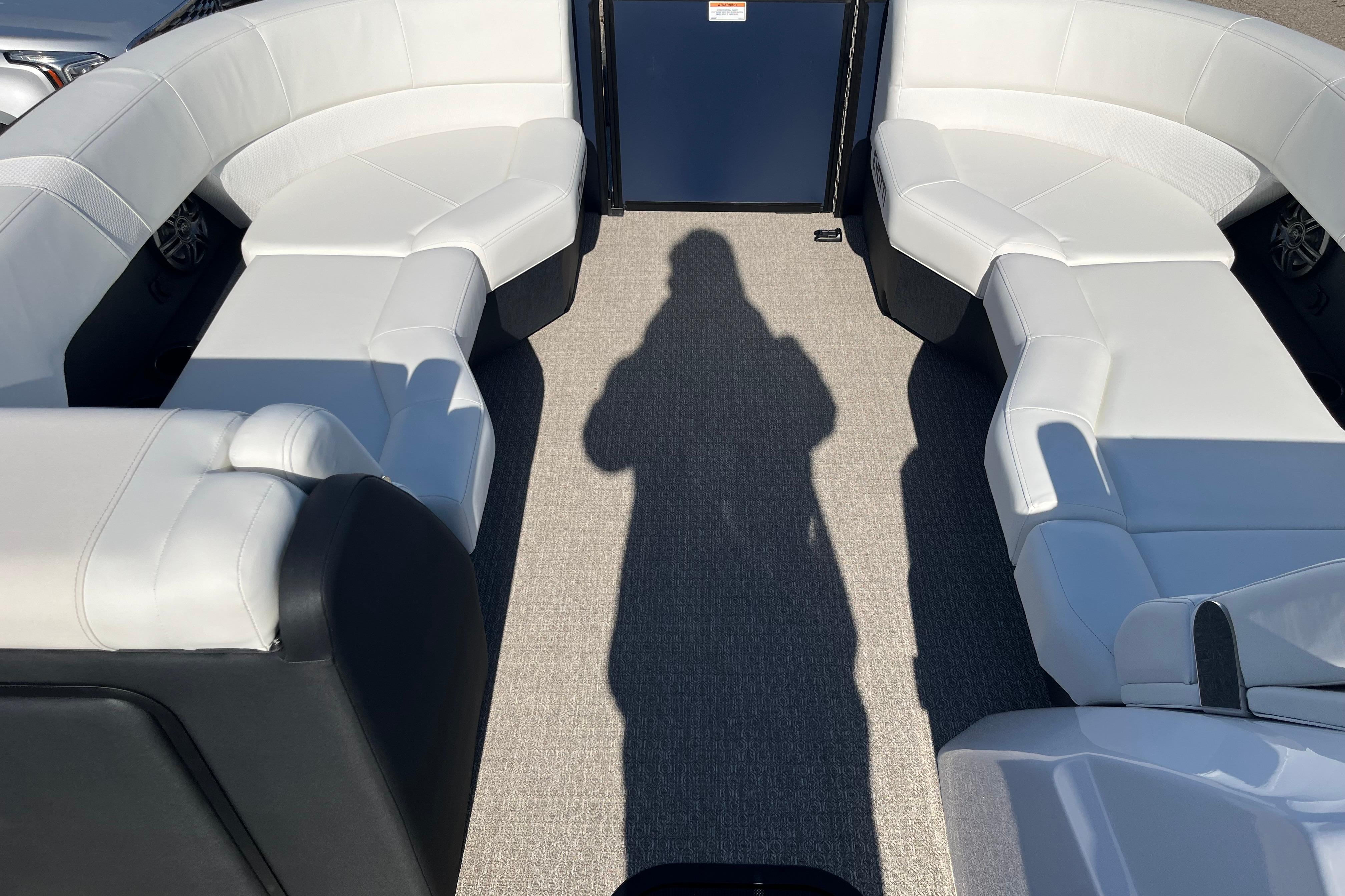 Interior of 2026 Evotti 523CS boat with white seating and shadow on carpet.