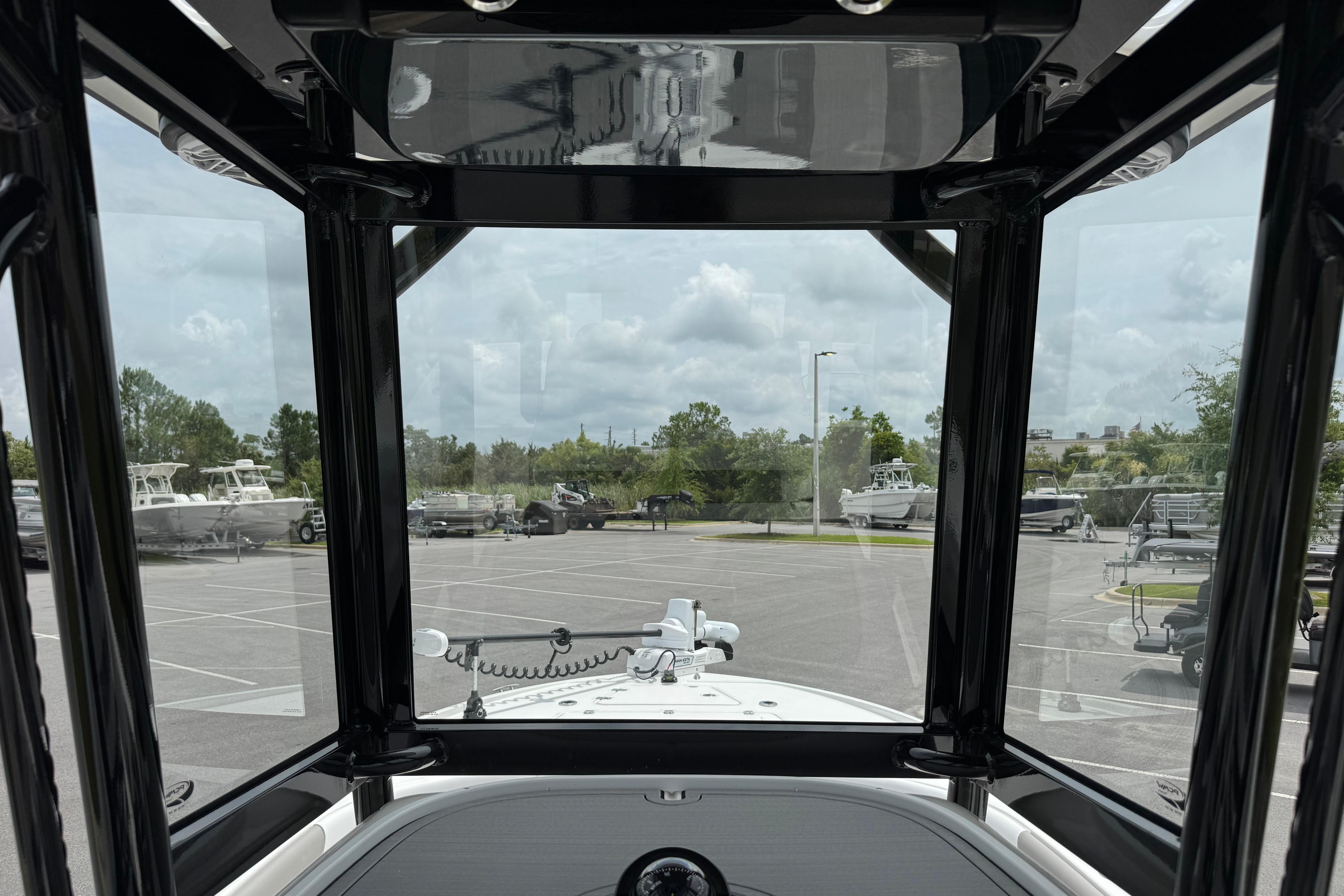 View from inside a 2027 Caymas 26 HB boat, showcasing the parking lot and surrounding trees.