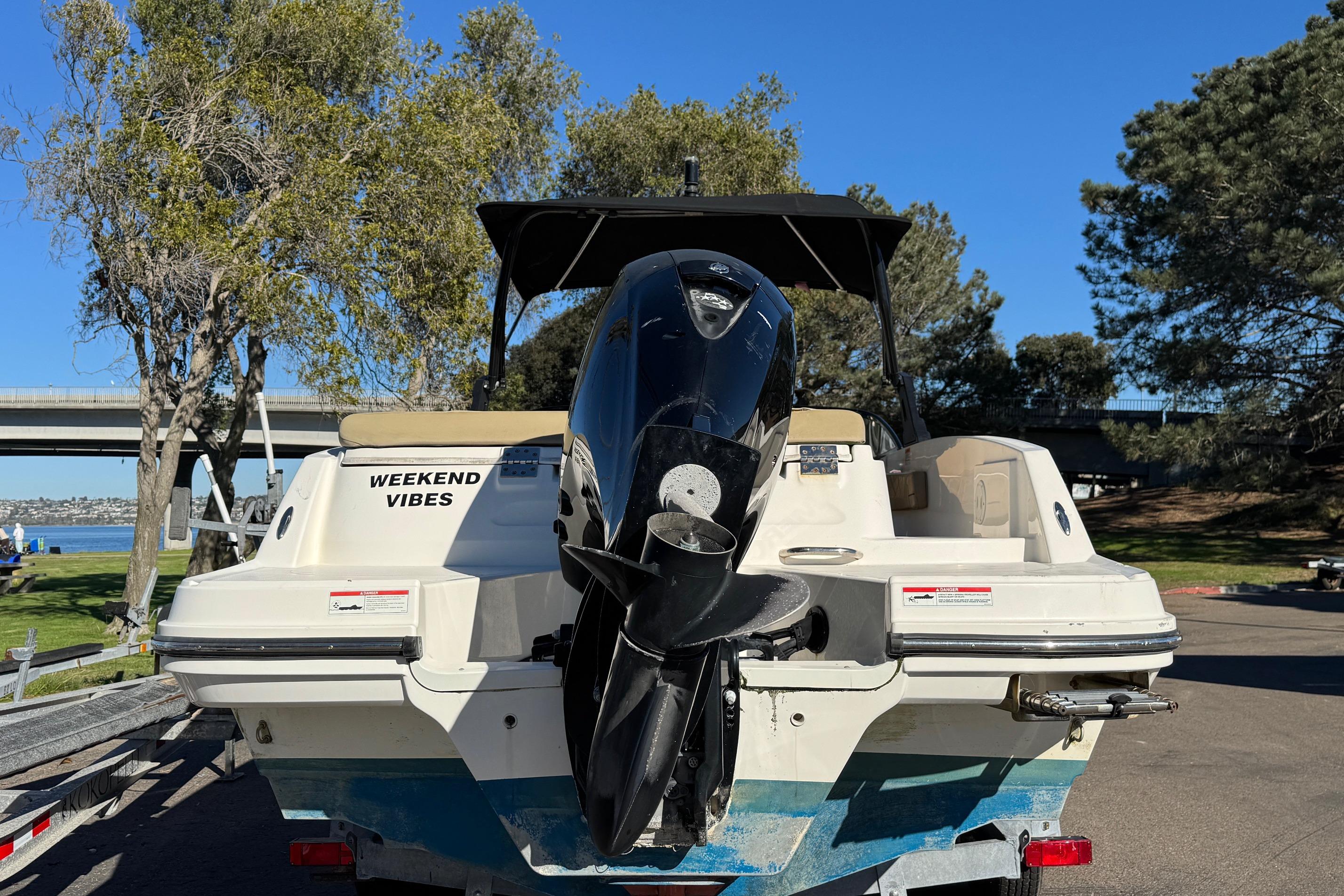 2022 Bayliner VR6 Bowrider OB boat with "Weekend Vibes" text, parked near a scenic lake.