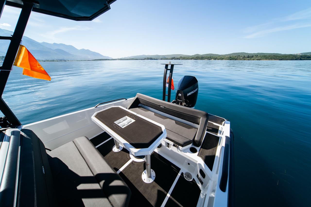 Custom 827 boat, 2024 model, with seating and table on a serene lake.