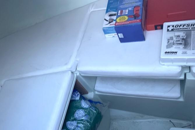 Interior of a 2002 Intrepid 323 Cuddy with emergency kit and supplies.